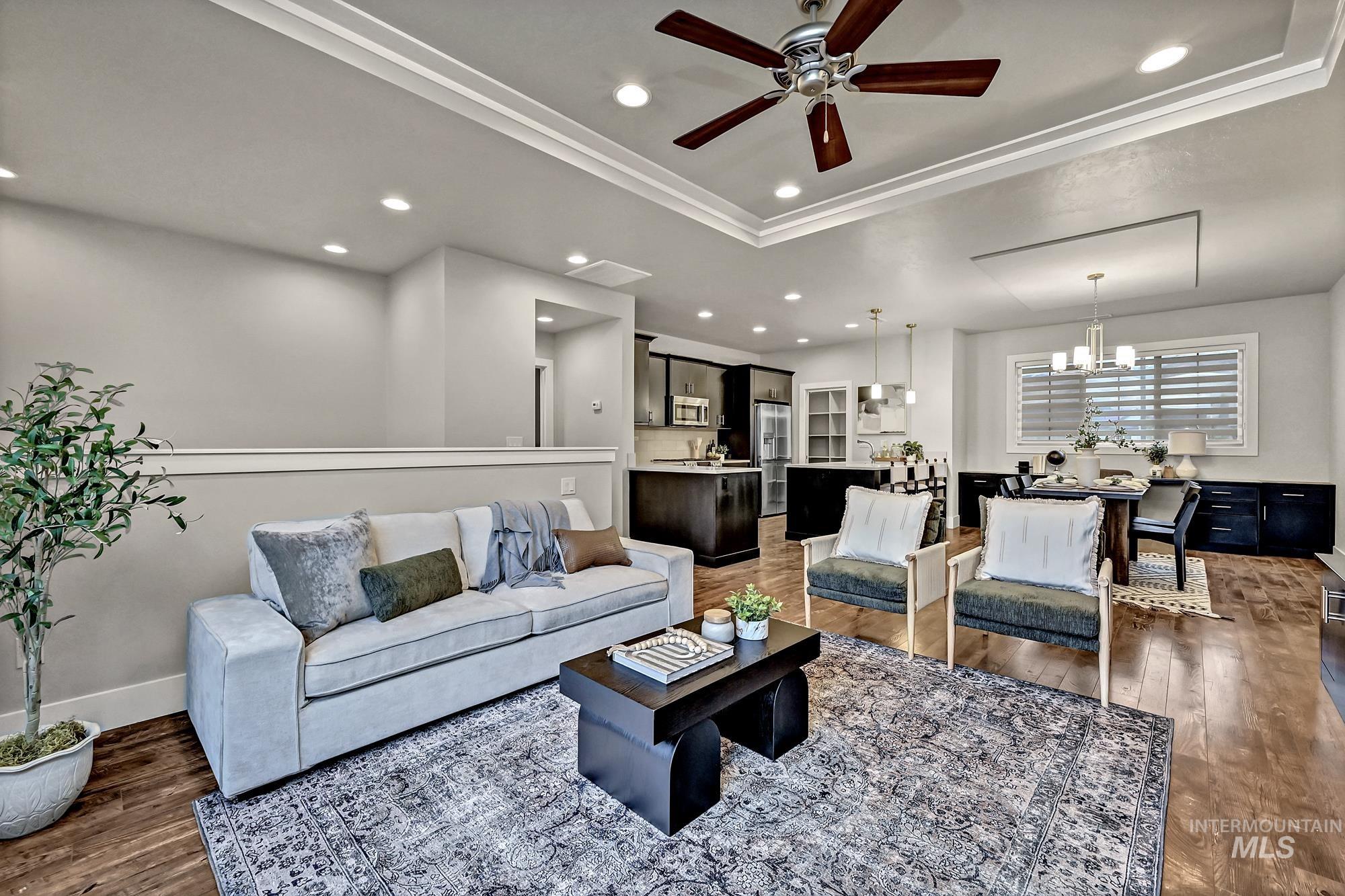 Living room with ceiling fan, dark wood-style flooring, recessed lighting, a chandelier, and ornamental molding