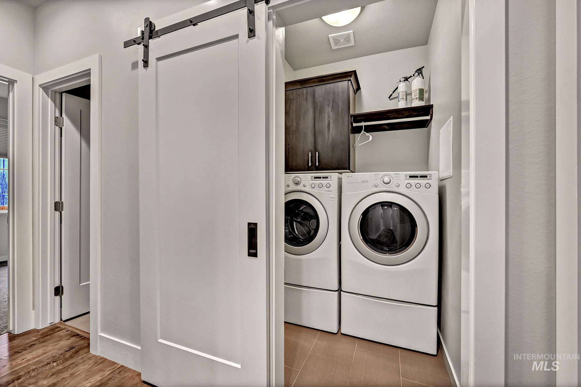 Laundry room with a barn door, cabinet space, and washer and clothes dryer