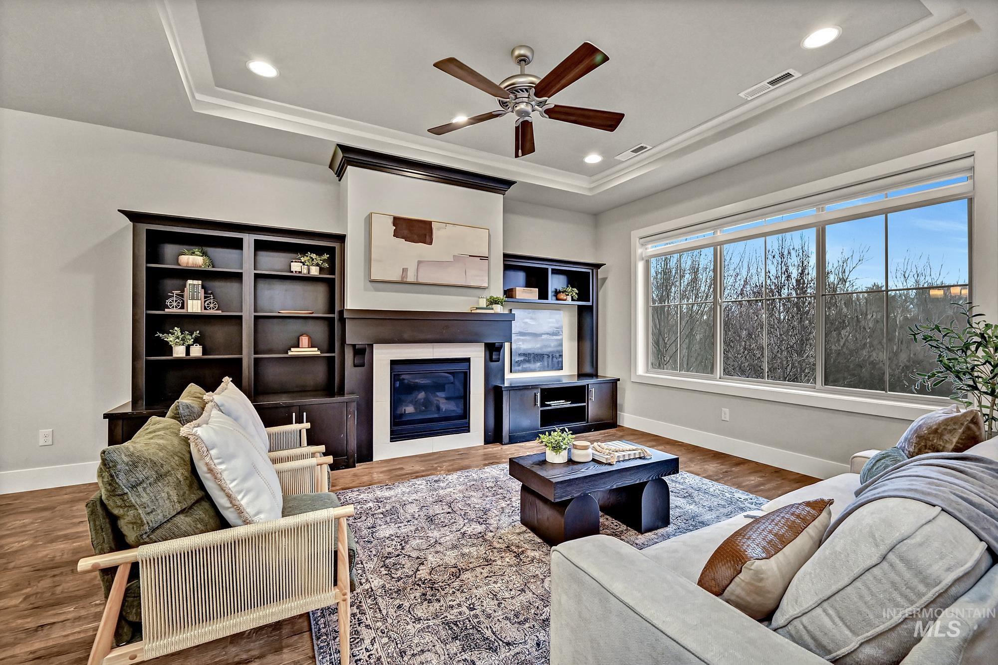Living room featuring a gas fireplace insert, high ceilings, ceiling fan, wood floors, and recessed lighting