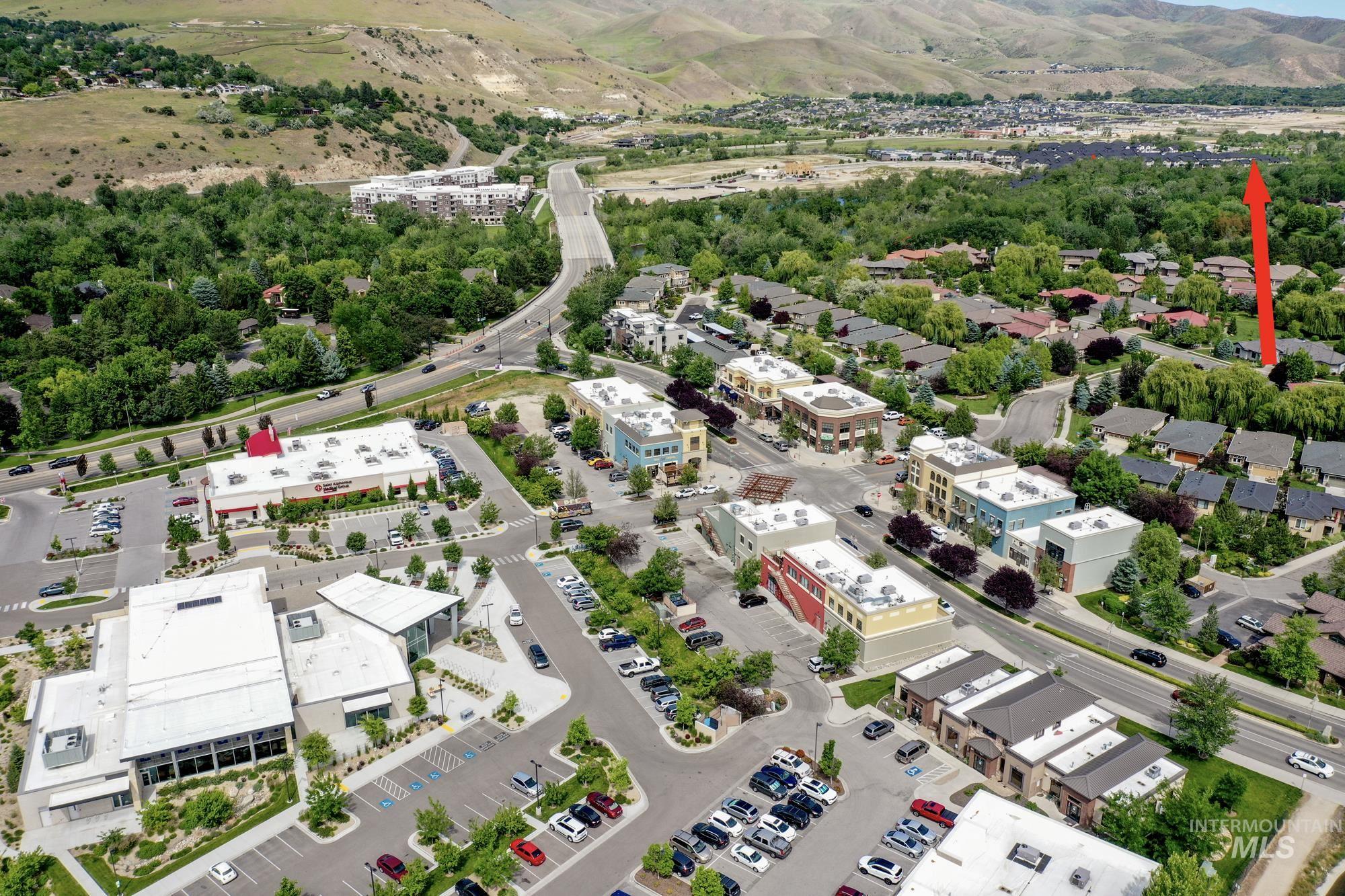 Aerial view of nearby Bown Crossing with shops, restaurants, coffee shops, & a branch of the Boise Library! with an arrow pointing to the home's location relative to it. Also shows a broad expanse of the beautiful Boise foothills.