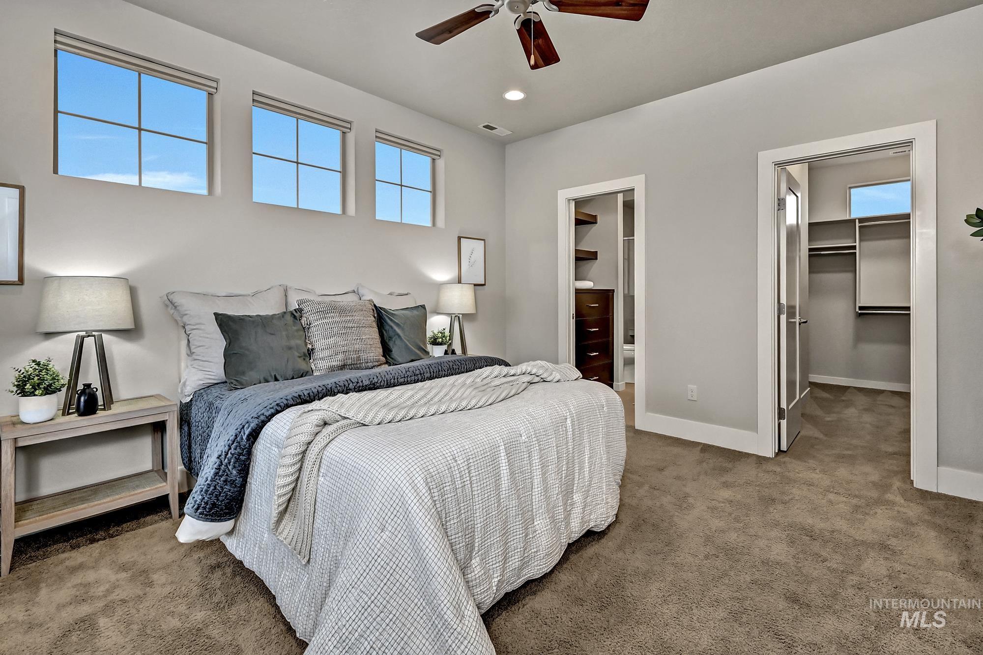 Carpeted bedroom with a spacious closet, a ceiling fan, large windows, and recessed lighting.