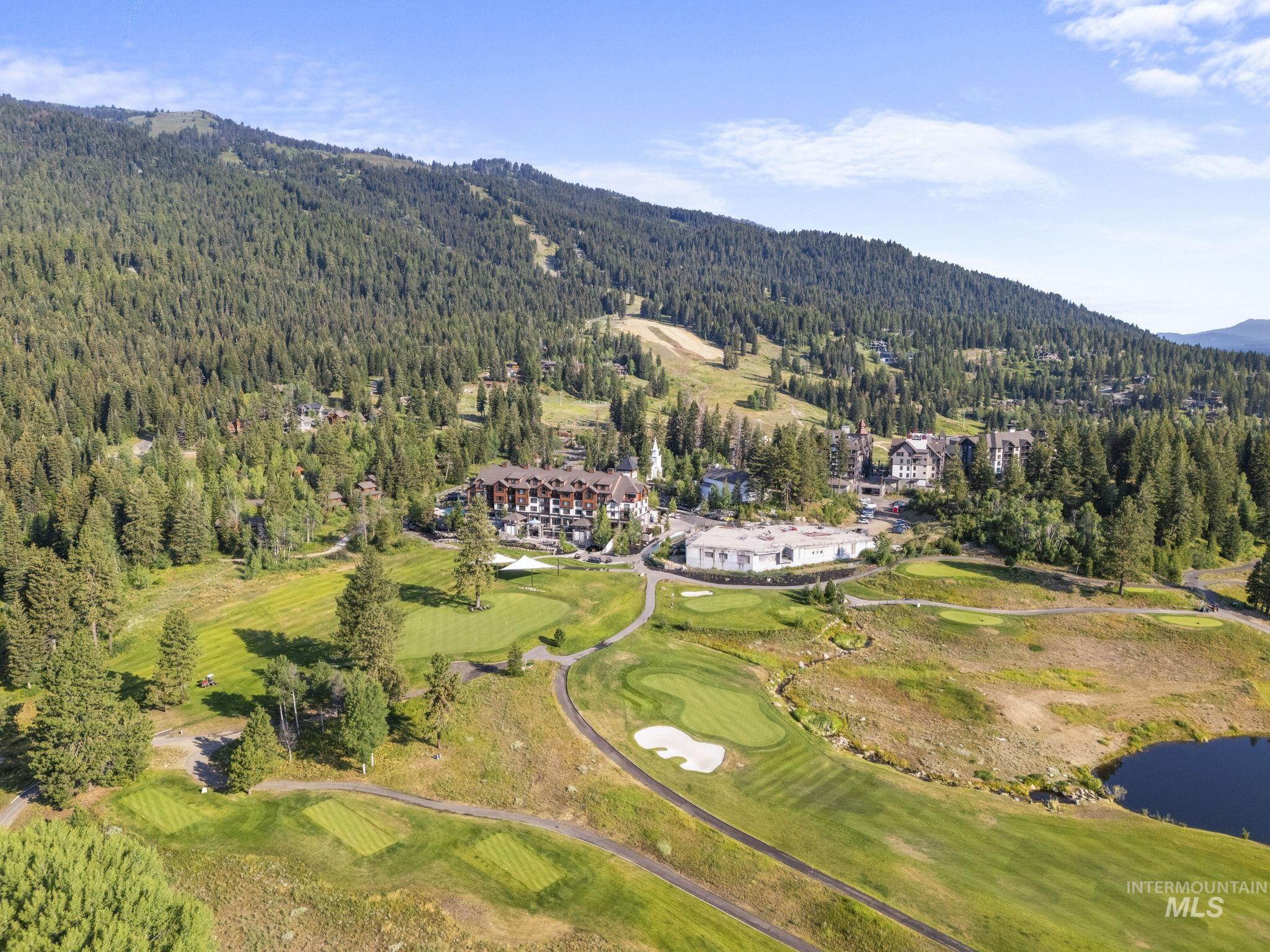 Aerial view of property and surrounding area featuring a local golf course and a water and mountain view