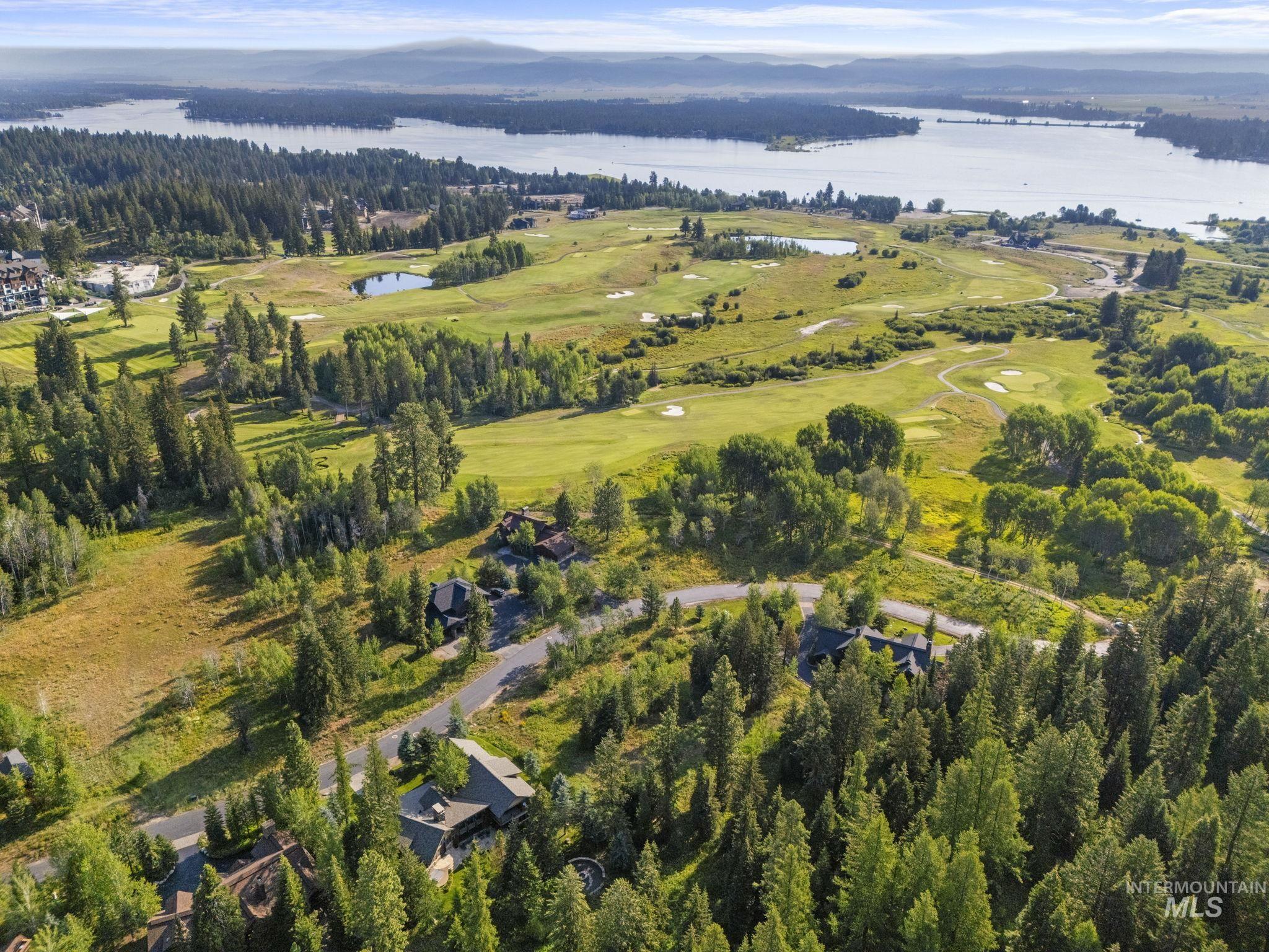 Aerial view of property and surrounding area featuring a nearby body of water and a local golf course