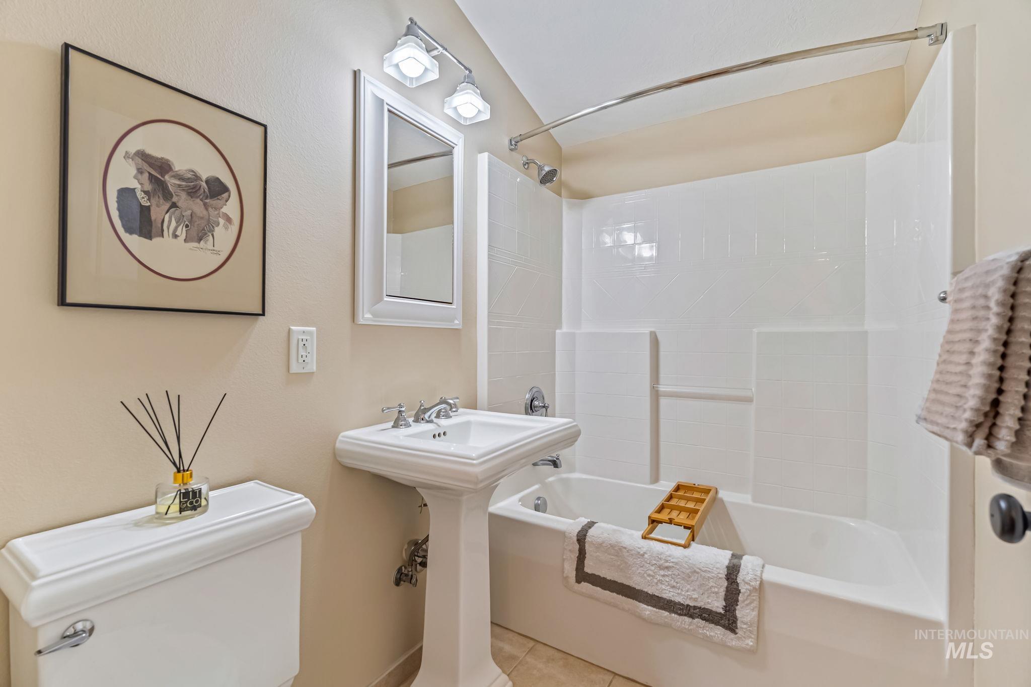 Bathroom with pedestal sink, shower / bath combination and light tile floors
