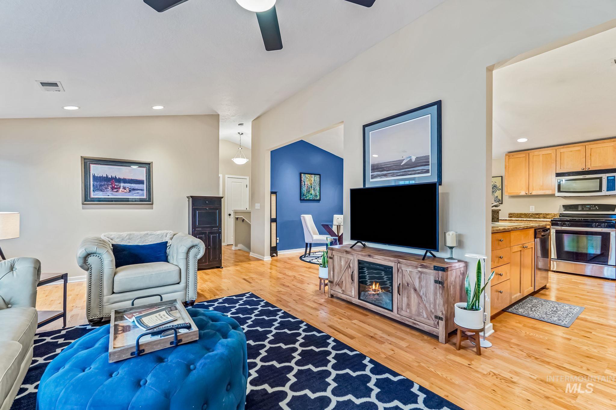 Living area with ceiling fan, light wood finished floors, vaulted ceiling, and recessed lighting