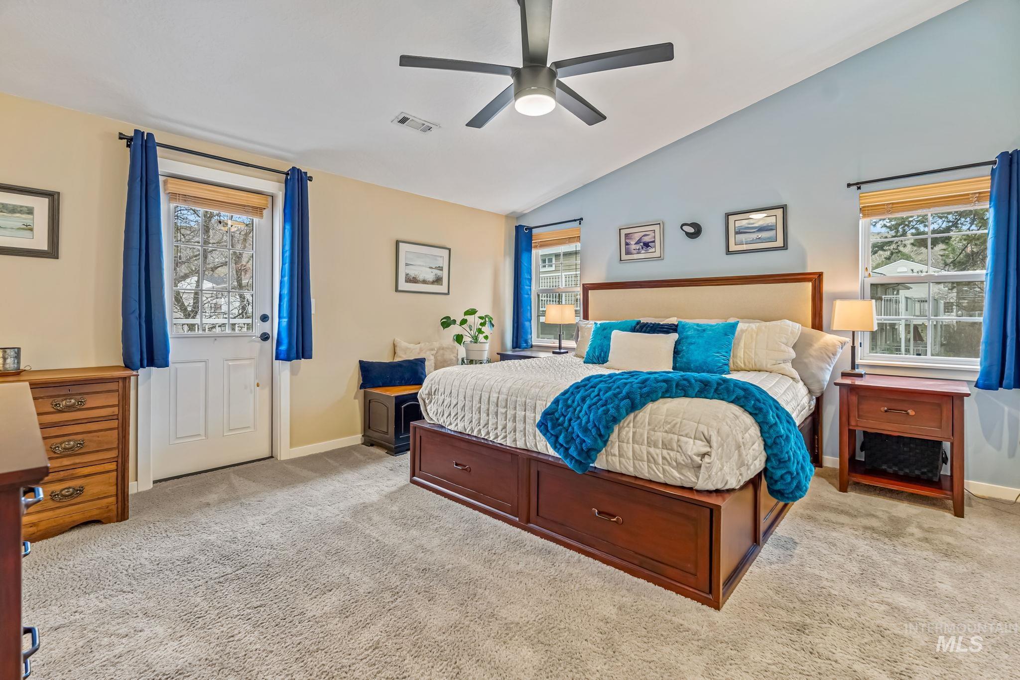 Spacious bedroom featuring a ceiling fan, vaulted ceiling, and light carpet
