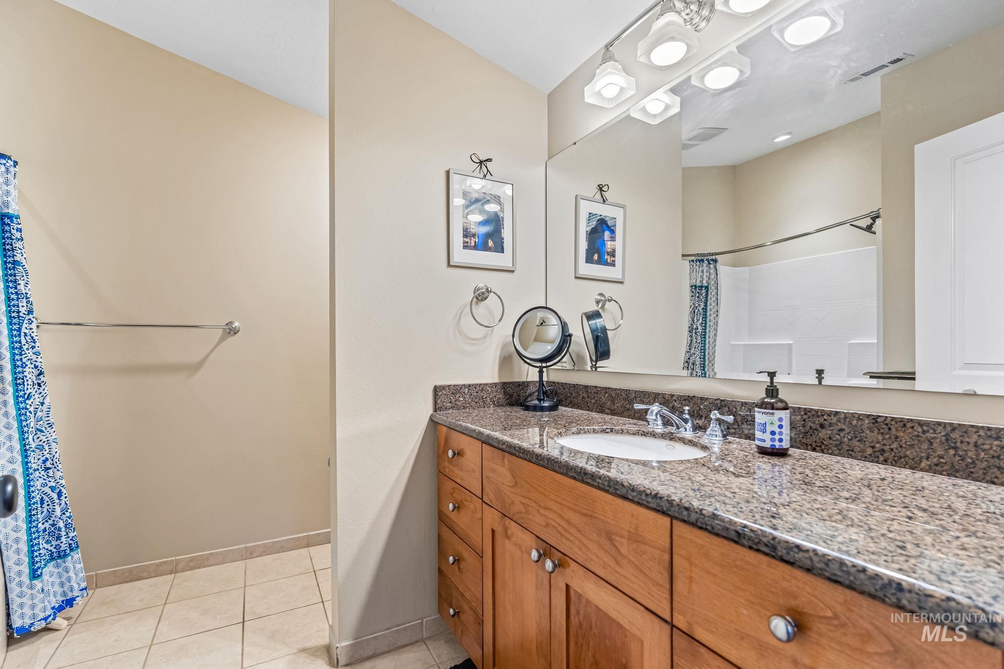 Bathroom with vanity, shower / tub combo, and light tile floors