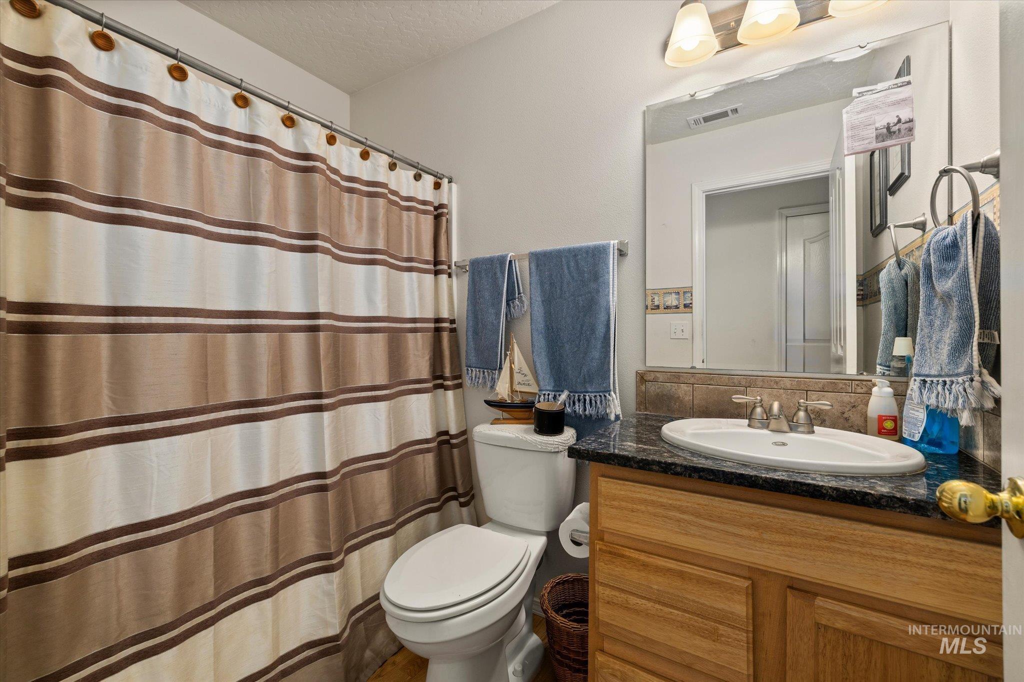Bathroom featuring a shower with curtain, vanity, and a textured ceiling