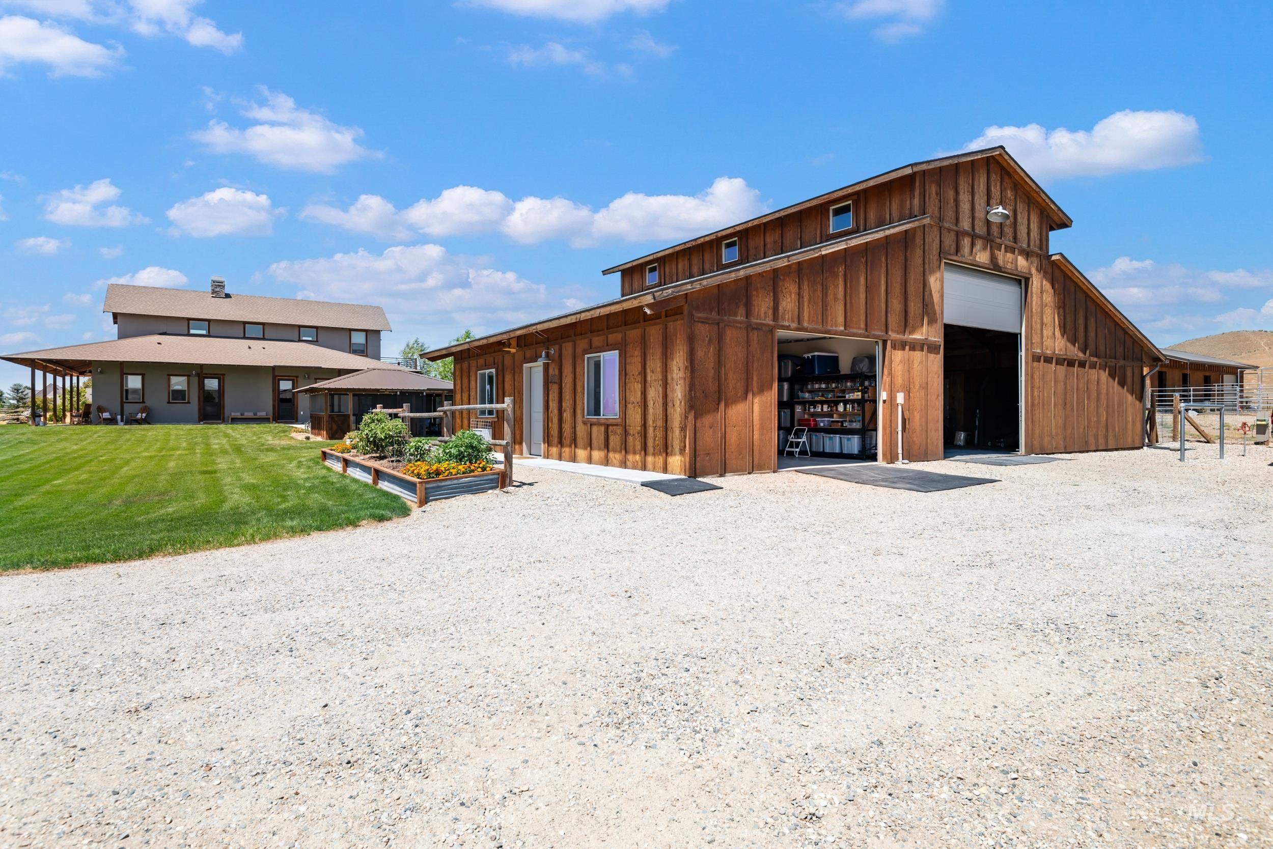 View of front of property featuring board and batten siding, a garage, an outdoor structure, a front yard, and an outbuilding
