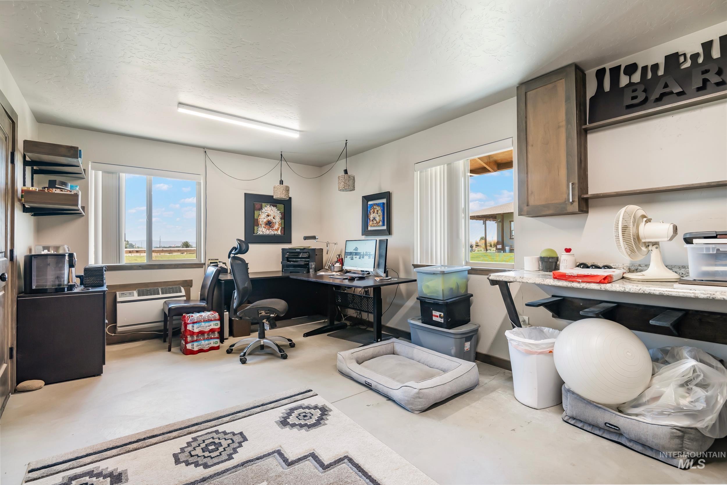 Office space with plenty of natural light, finished concrete floors, and a textured ceiling