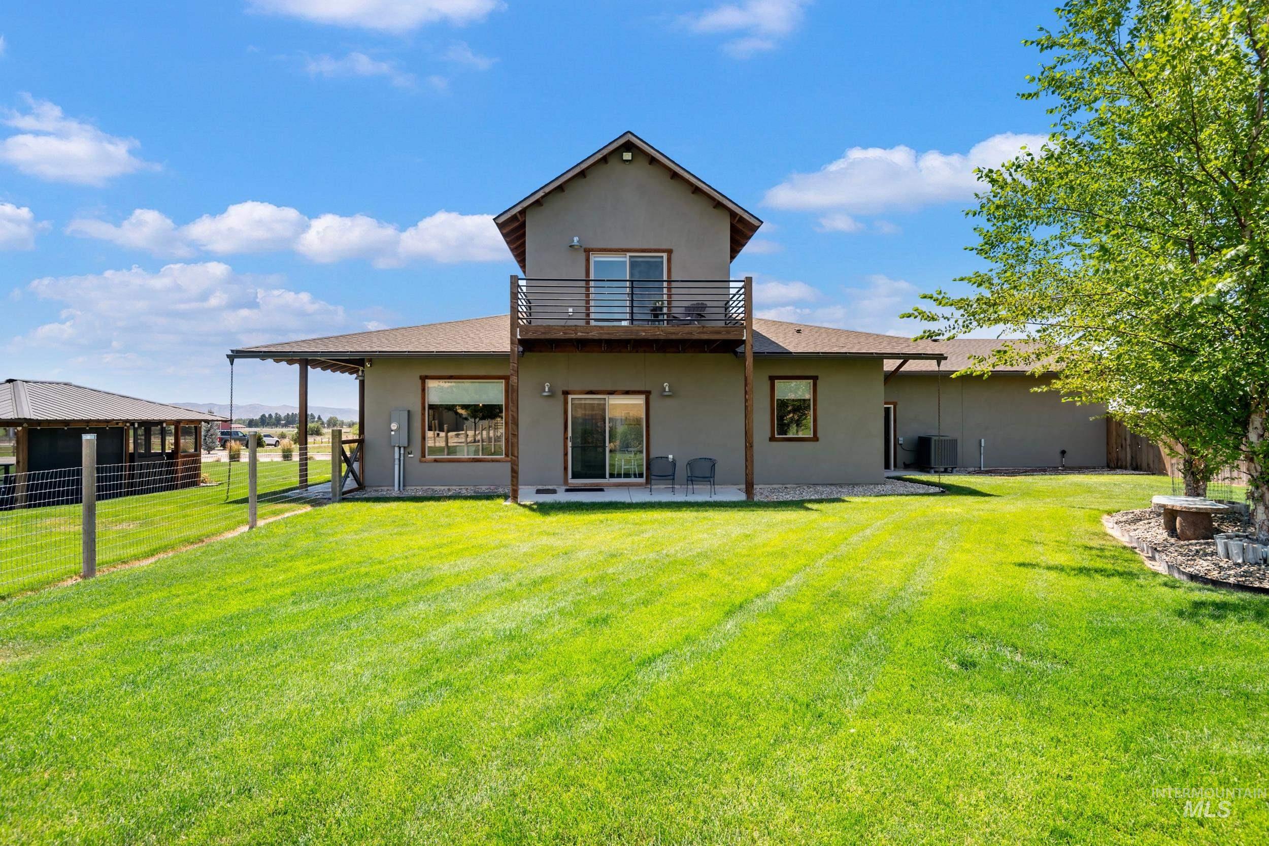 Rear view of house featuring a balcony, stucco siding, and a patio