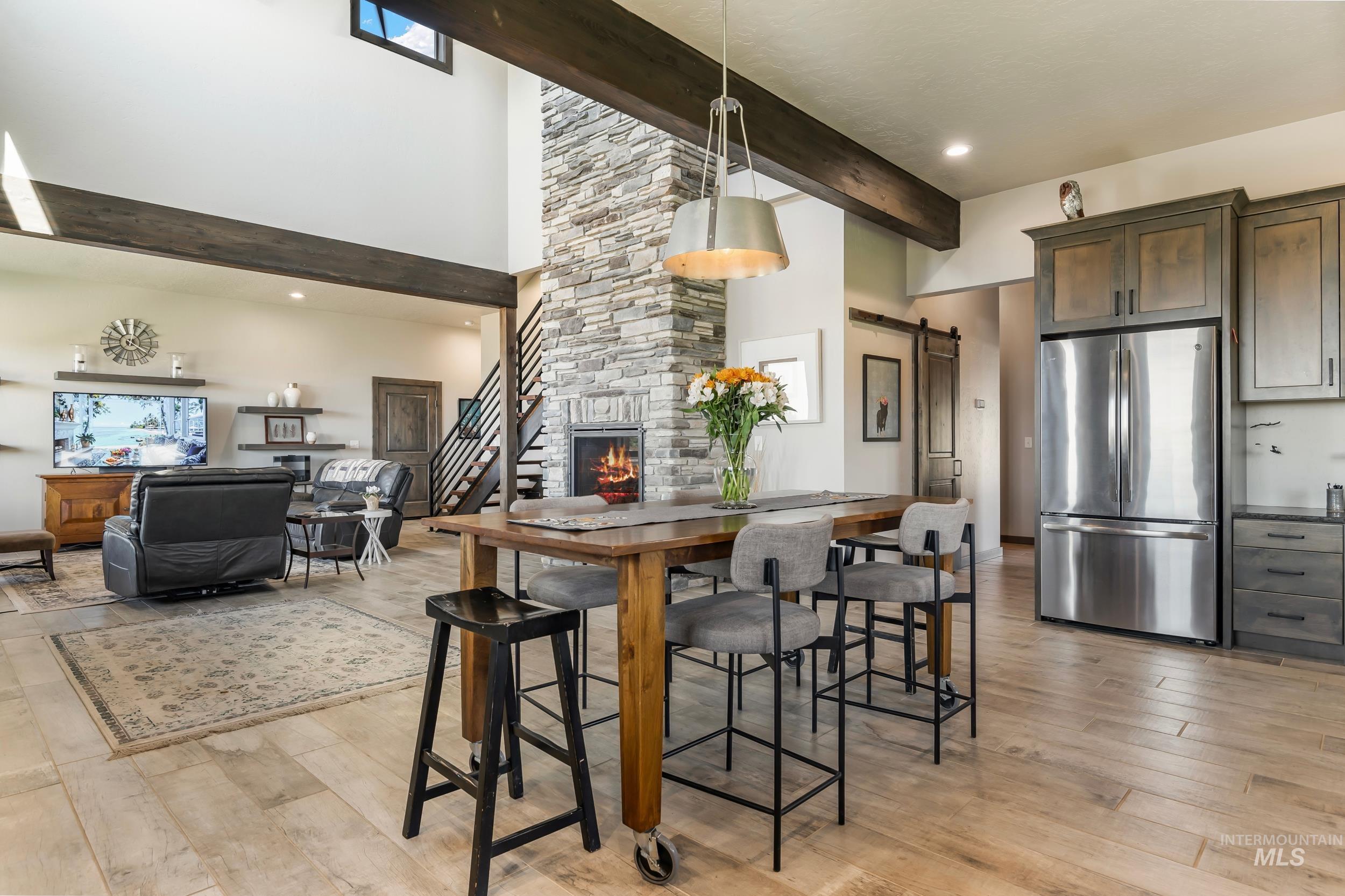 Kitchen featuring freestanding refrigerator, beam ceiling, a high ceiling, a barn door, and light wood-style flooring