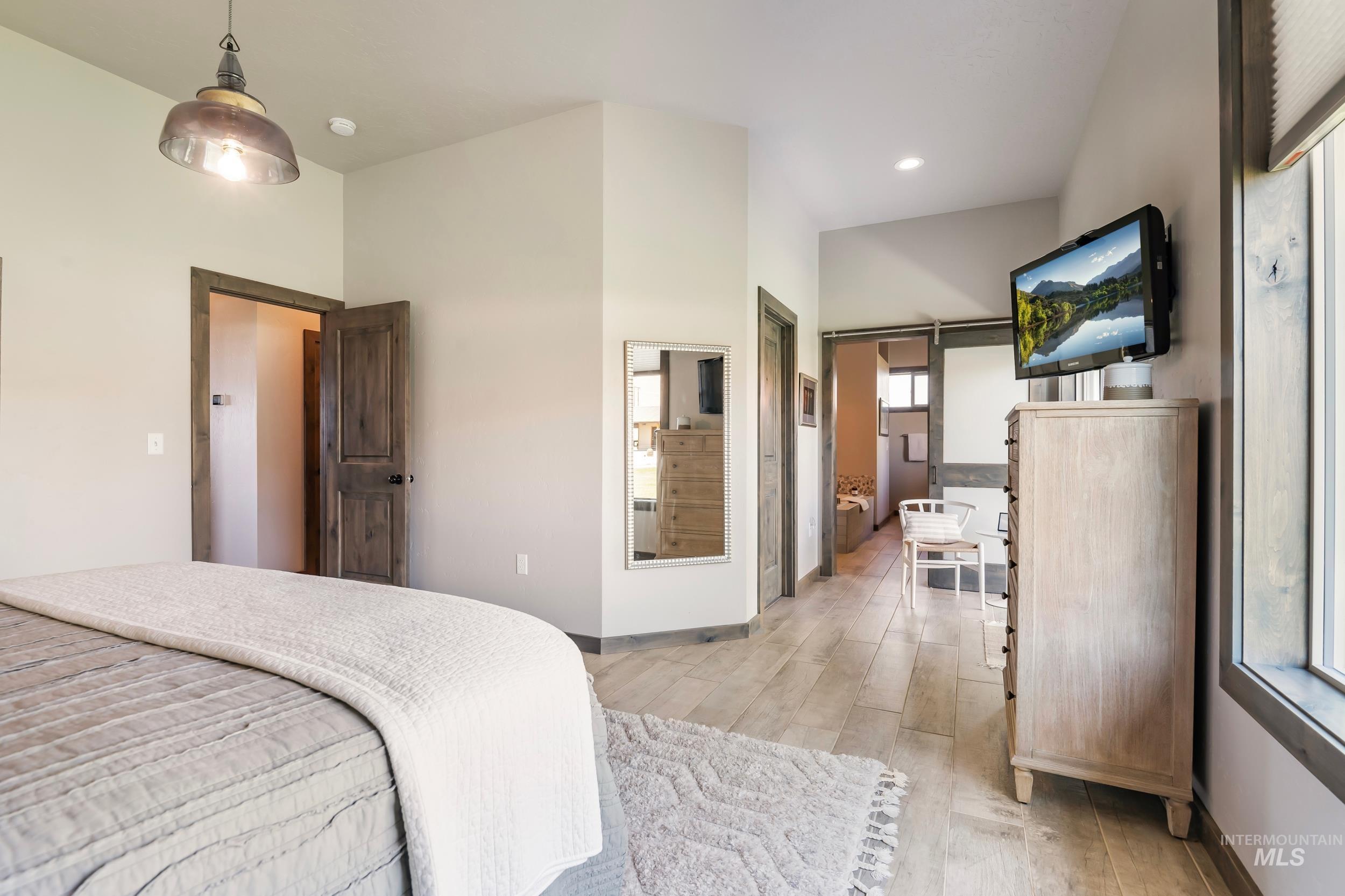 Bedroom with light wood-style flooring, a high ceiling, and recessed lighting