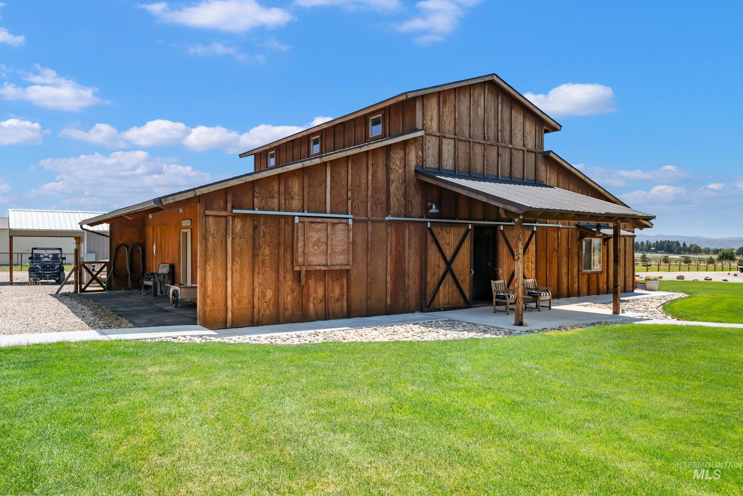 Rear view of house featuring board and batten siding, a barn, a yard, and an outbuilding