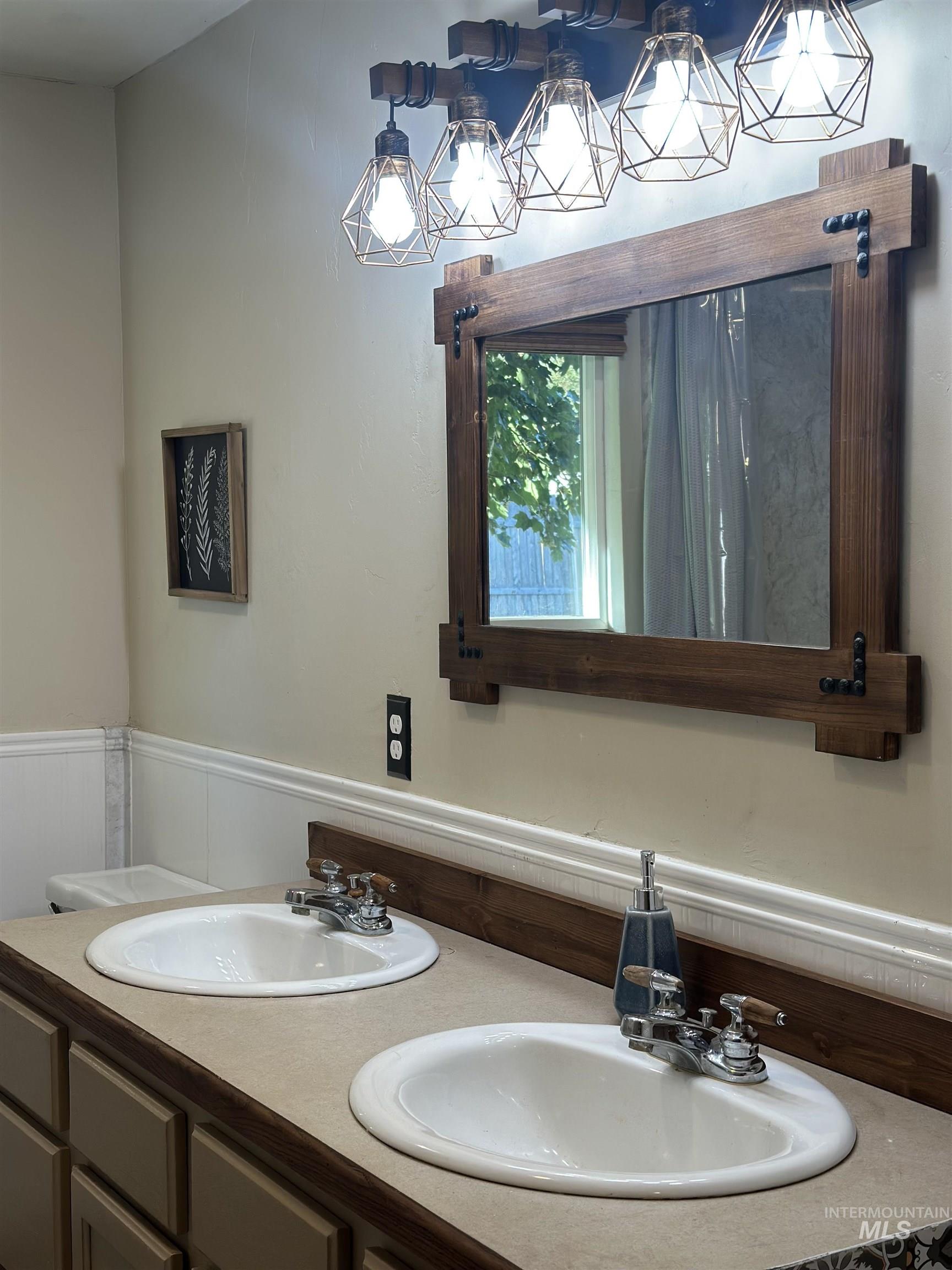 Full bath with double vanity and a wainscoted wall