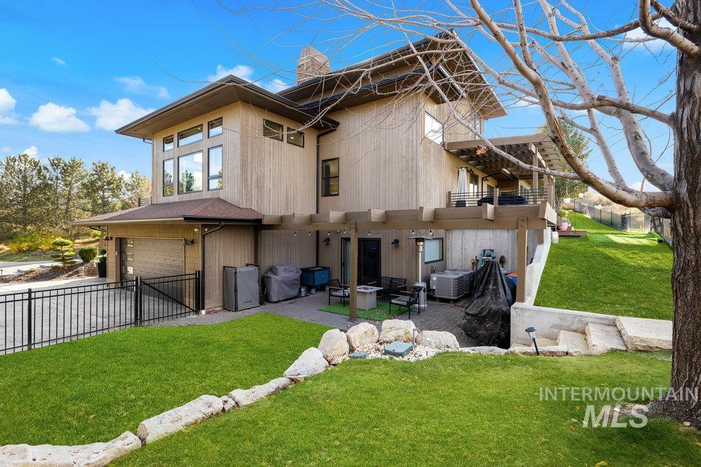 Back of house with a patio, a chimney, an attached garage, and driveway