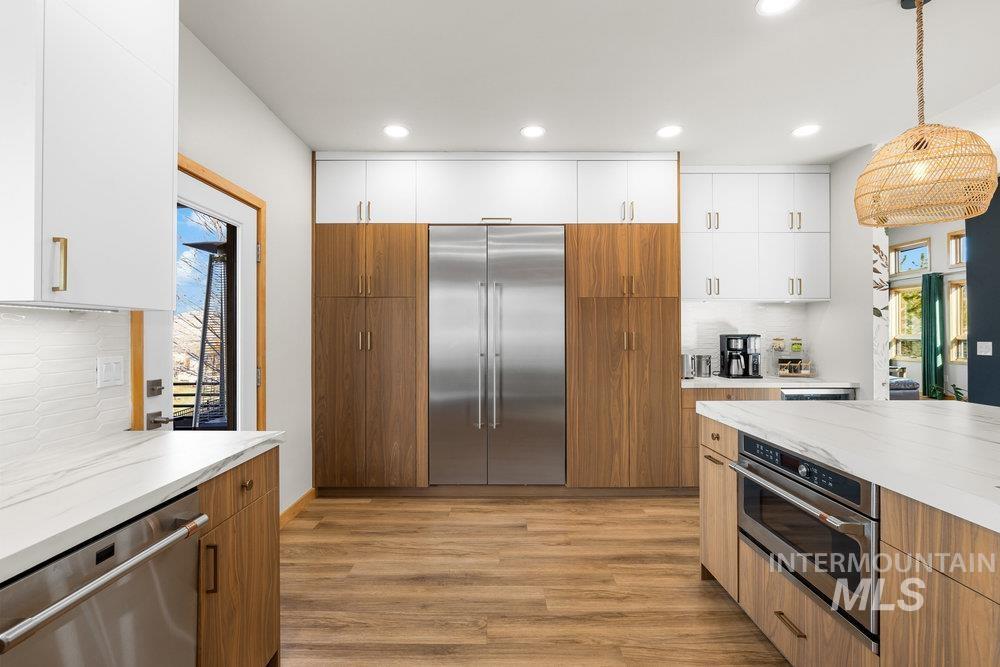 Kitchen with backsplash, brown cabinets, white cabinets, and recessed lighting