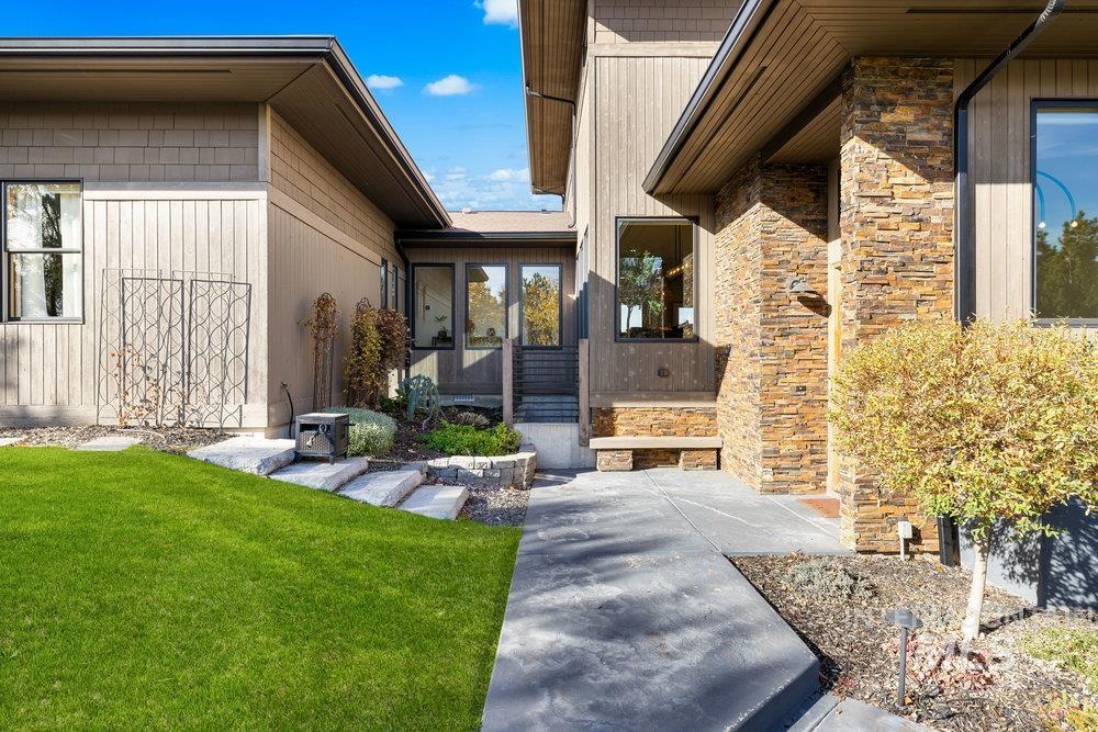 Doorway to property featuring stone siding and a lawn
