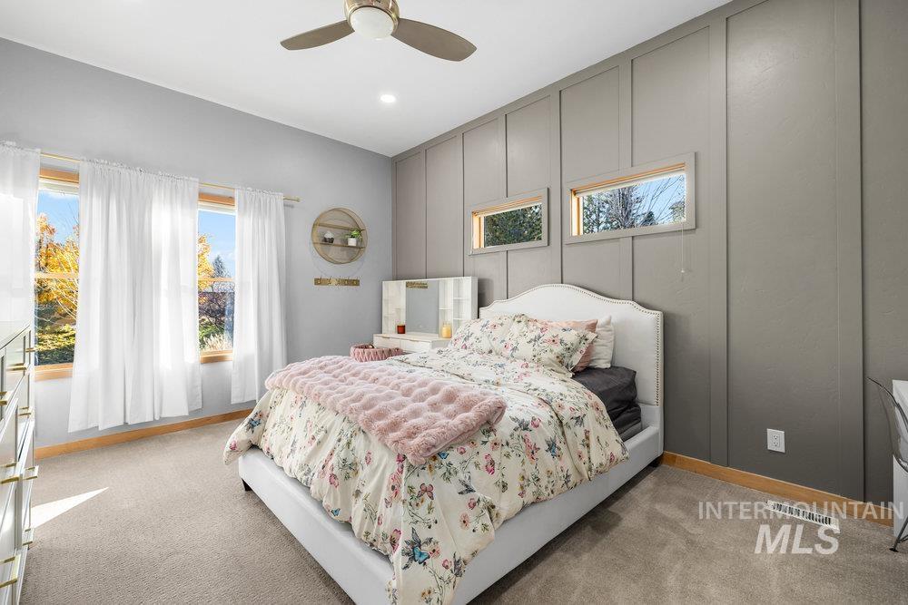 Bedroom with light carpet, a decorative wall, a ceiling fan, and recessed lighting