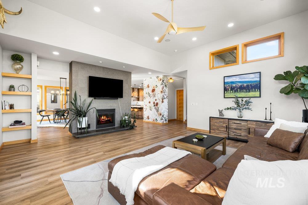Living room with wood finished floors, a ceiling fan, recessed lighting, and a fireplace