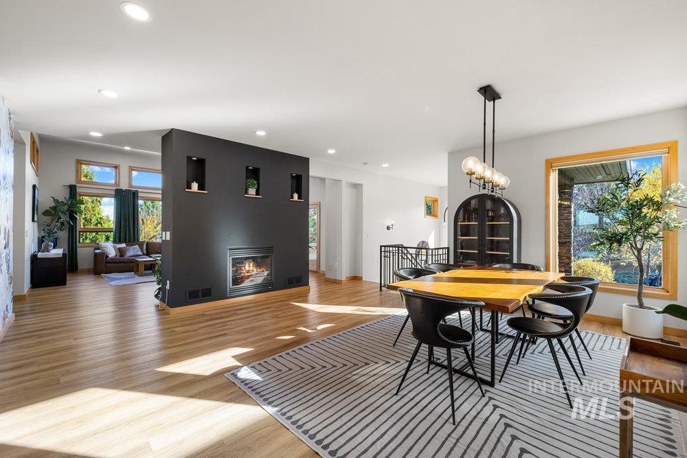 Dining space with light wood-type flooring, recessed lighting, a glass covered fireplace, and a chandelier