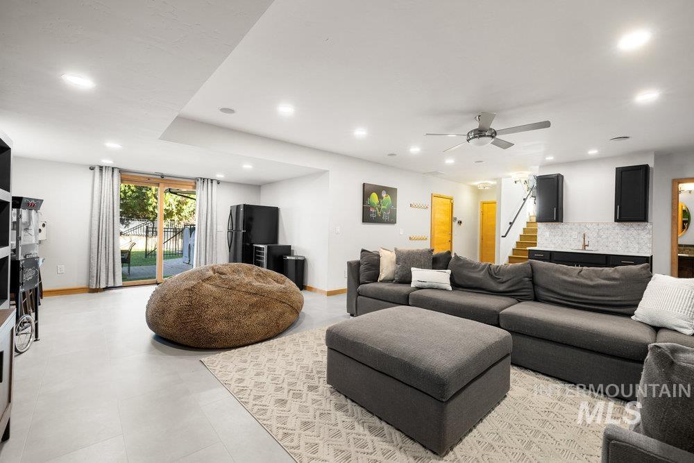 Living area with recessed lighting, ceiling fan, and stairway