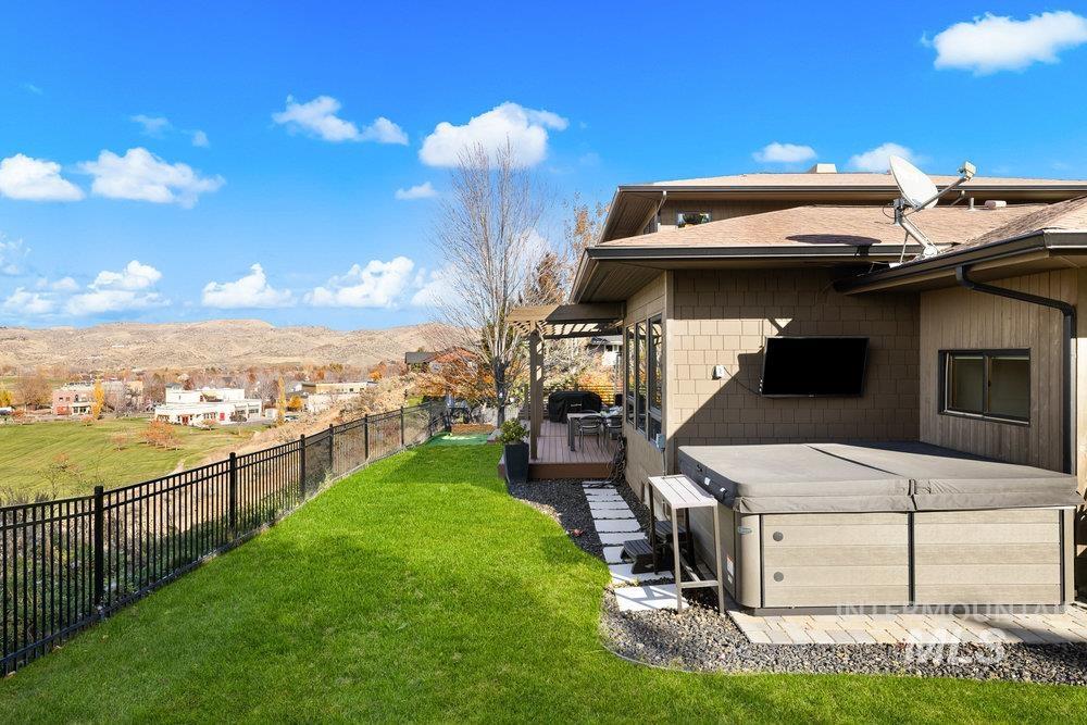 Fenced backyard featuring a hot tub and a wooden deck