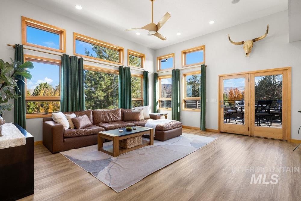 Living area featuring light wood-style flooring, ceiling fan, recessed lighting, and a towering ceiling