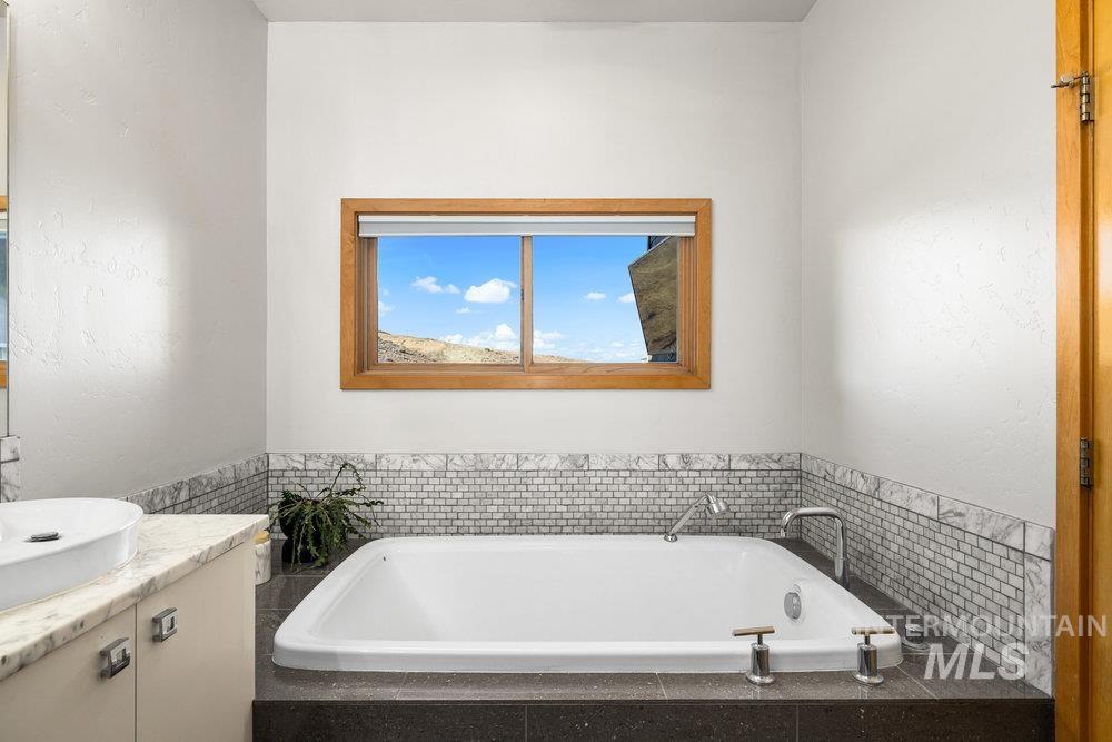 Full bathroom featuring a garden tub and vanity