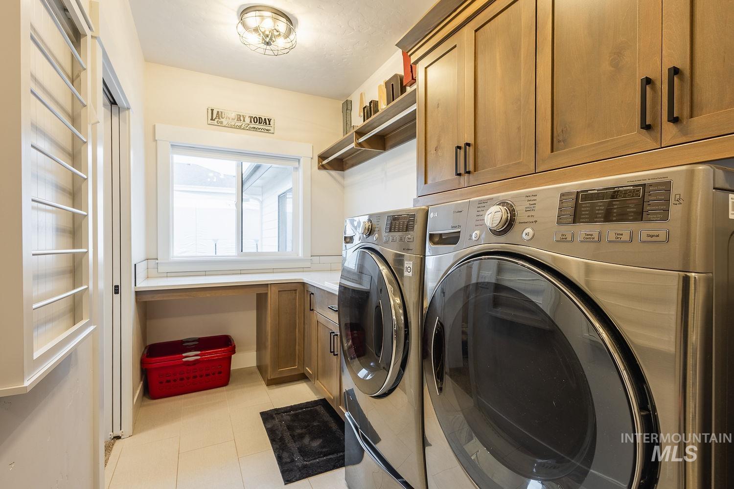 Washroom featuring washing machine and clothes dryer, cabinet space, and light tile patterned floors