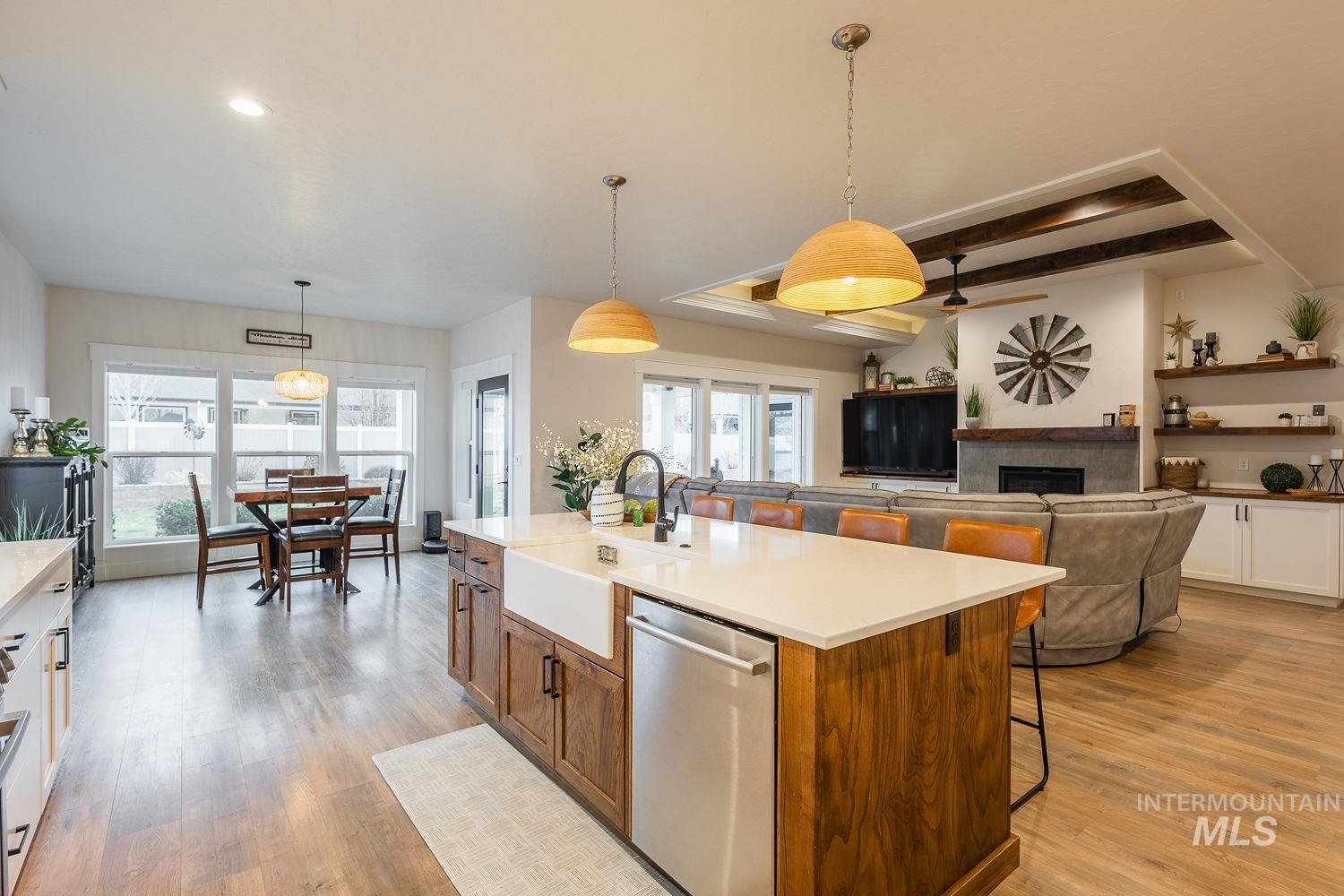 Kitchen featuring stainless steel dishwasher, open floor plan, hanging light fixtures, a breakfast bar area, and light wood finished floors