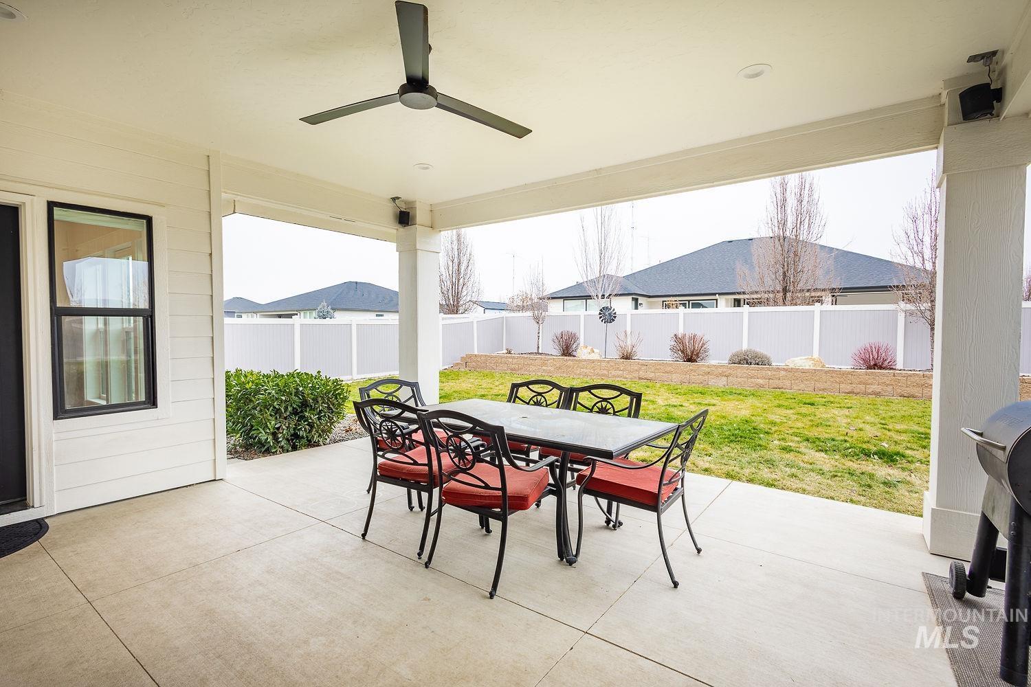 Fenced backyard featuring outdoor dining area, a patio area, and a ceiling fan