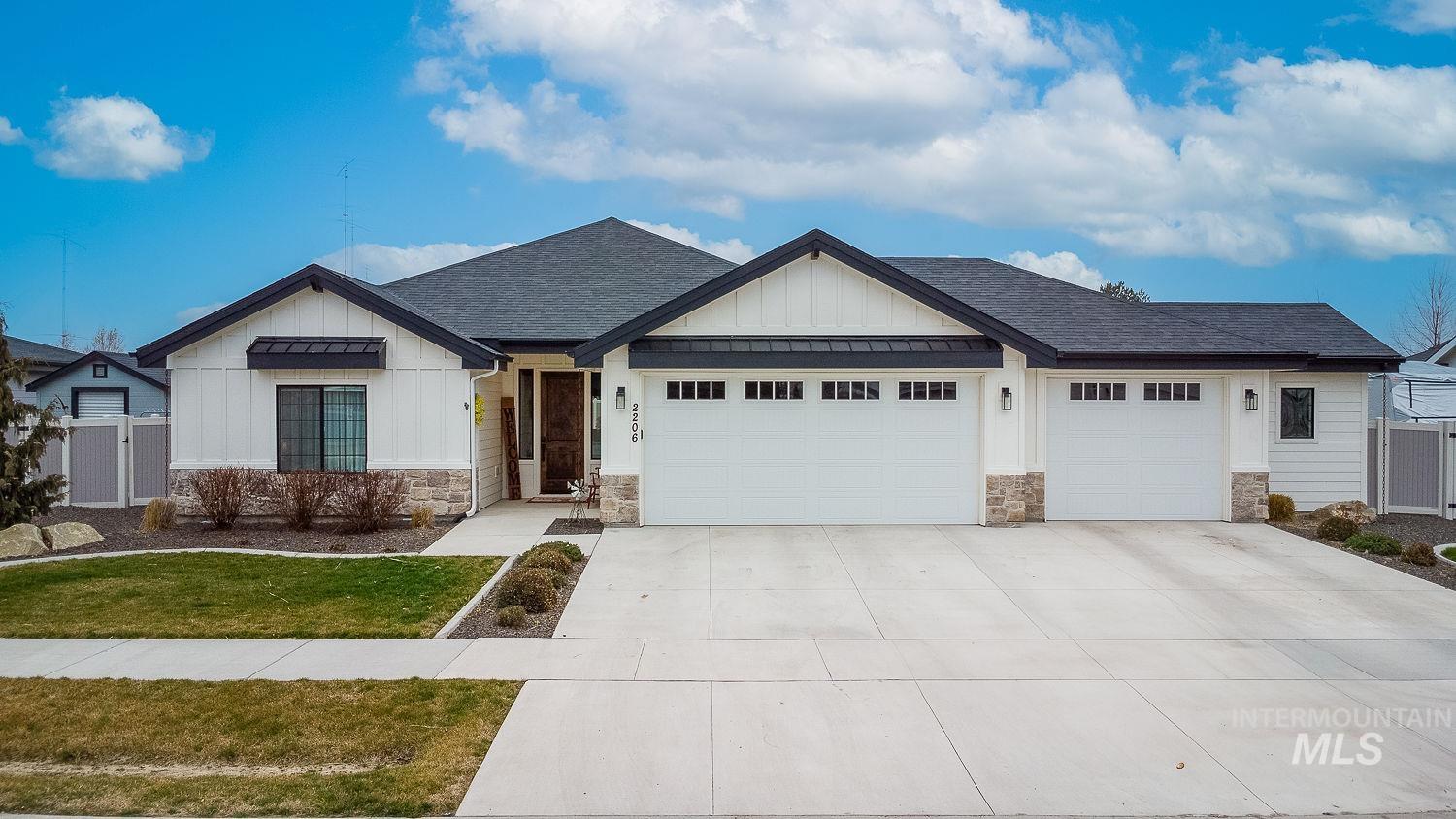 Modern farmhouse style home featuring board and batten siding, a shingled roof, stone siding, and a garage