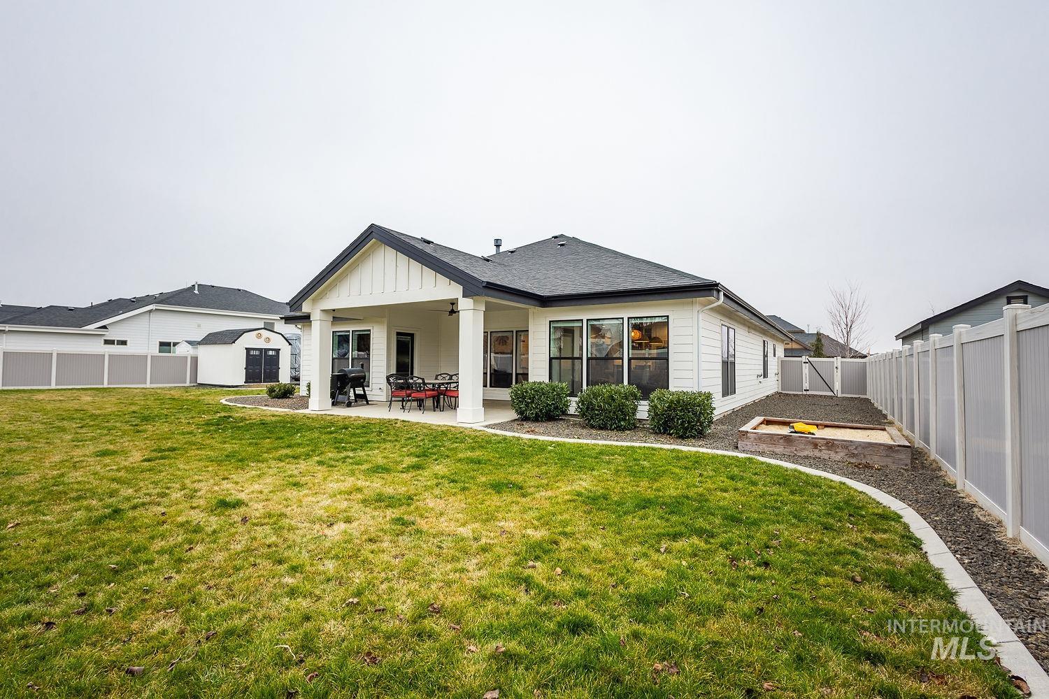 Rear view of house with a fenced backyard, a patio, ceiling fan, board and batten siding, and a shingled roof