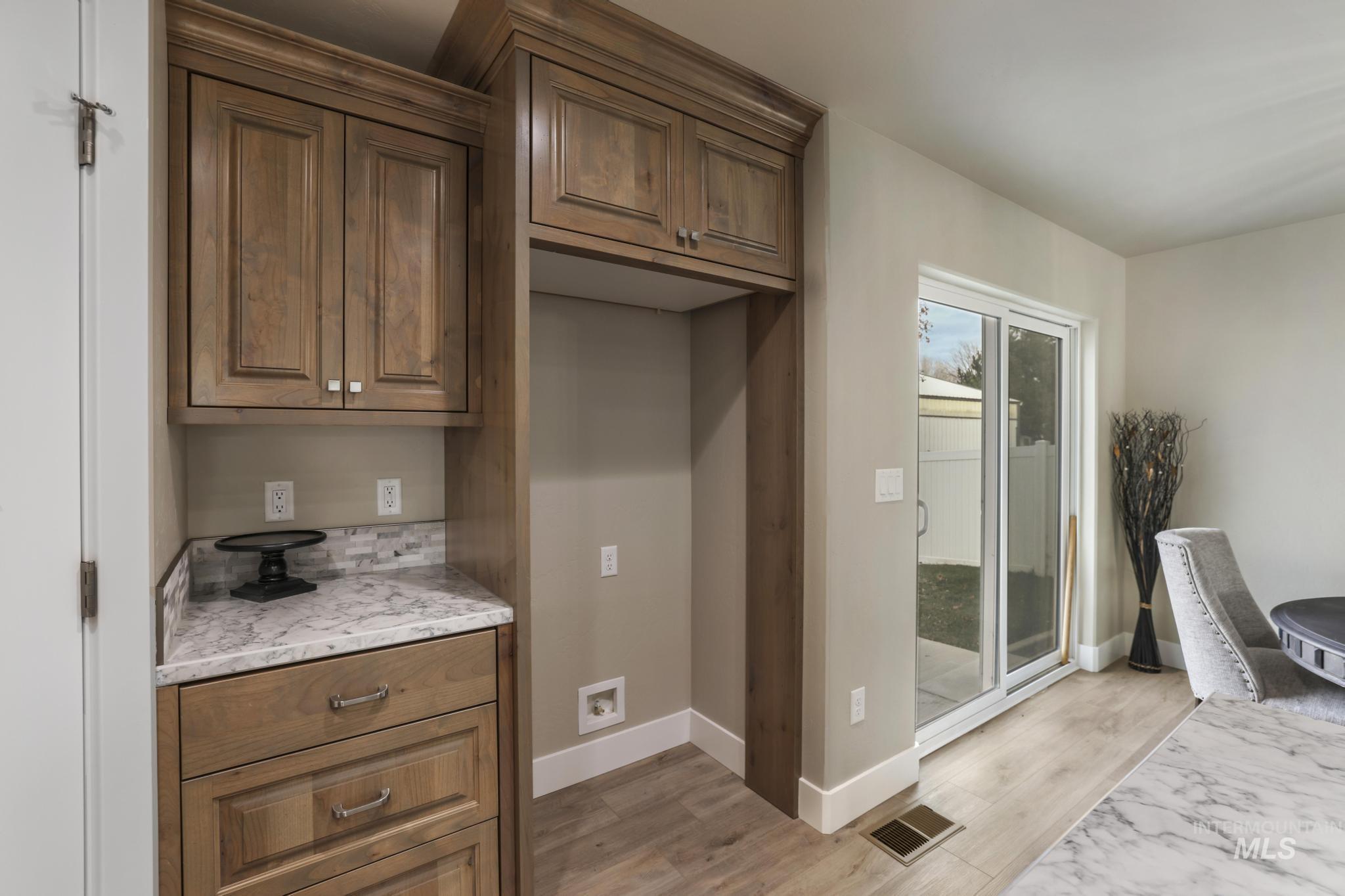 Kitchen with brown cabinets, light wood-style floors, and light stone counters