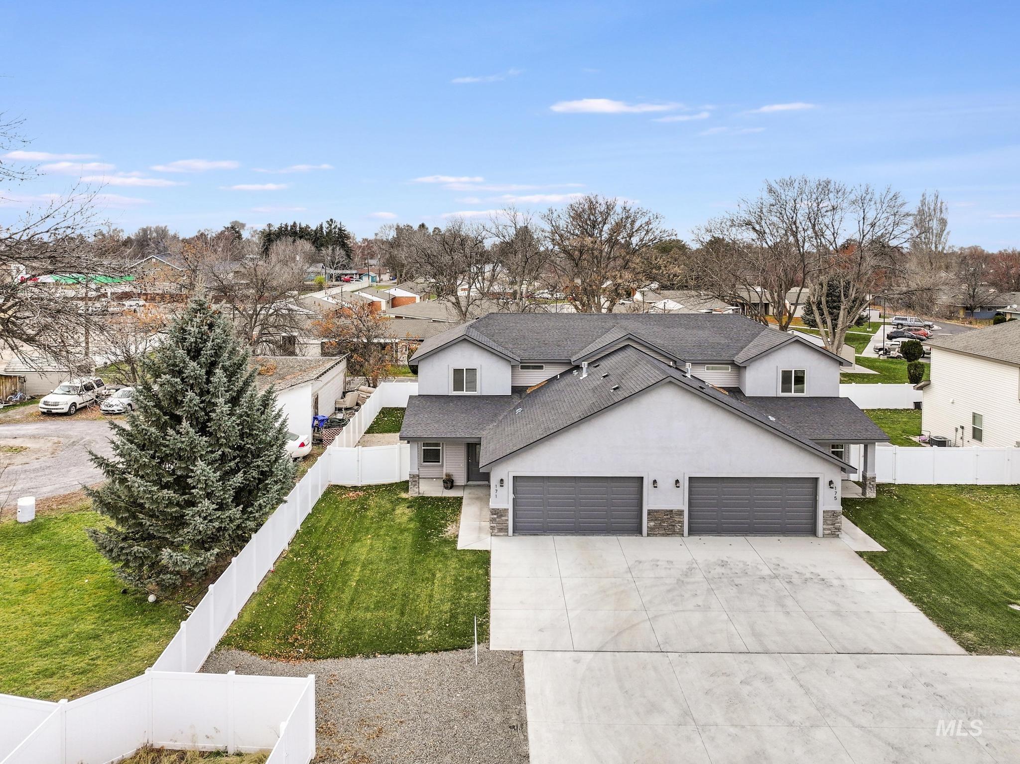 View of front of property with a fenced backyard, stucco siding, driveway, stone siding, and a shingled roof