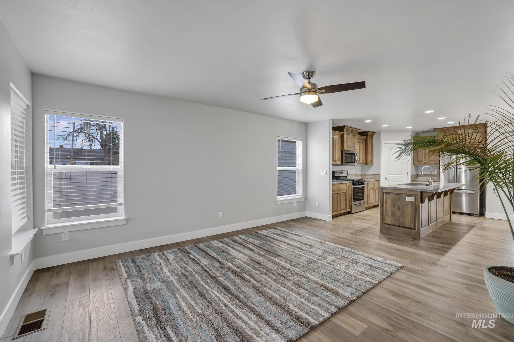 Unfurnished living room featuring recessed lighting, light wood finished floors, ceiling fan, and plenty of natural light
