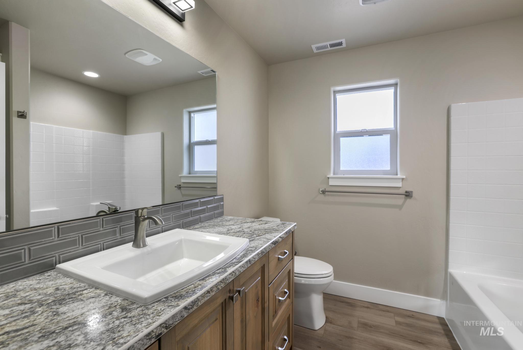 Full bathroom featuring vanity, dark wood-type flooring, and  shower combination