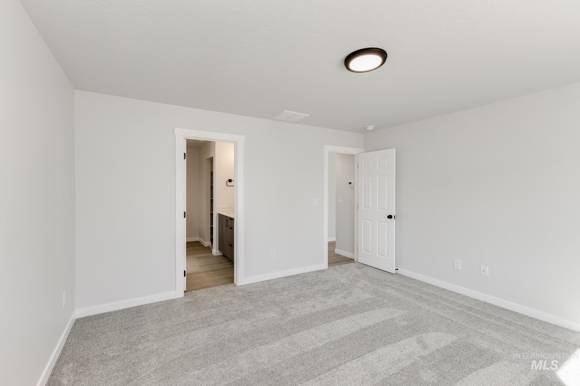 Unfurnished bedroom with light carpet and connected bathroom