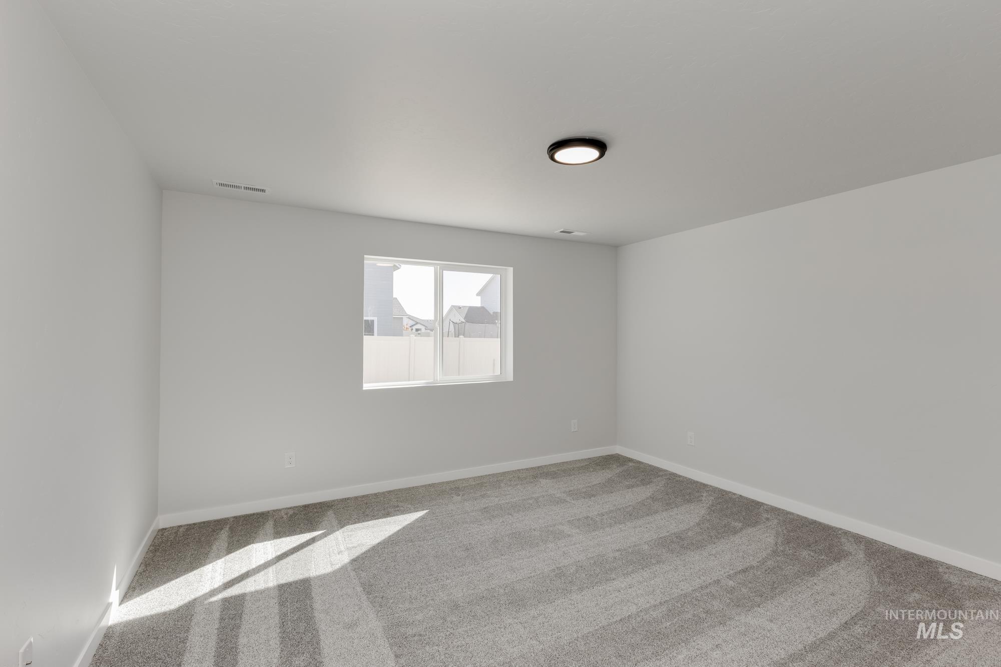 Carpeted spare room featuring baseboards