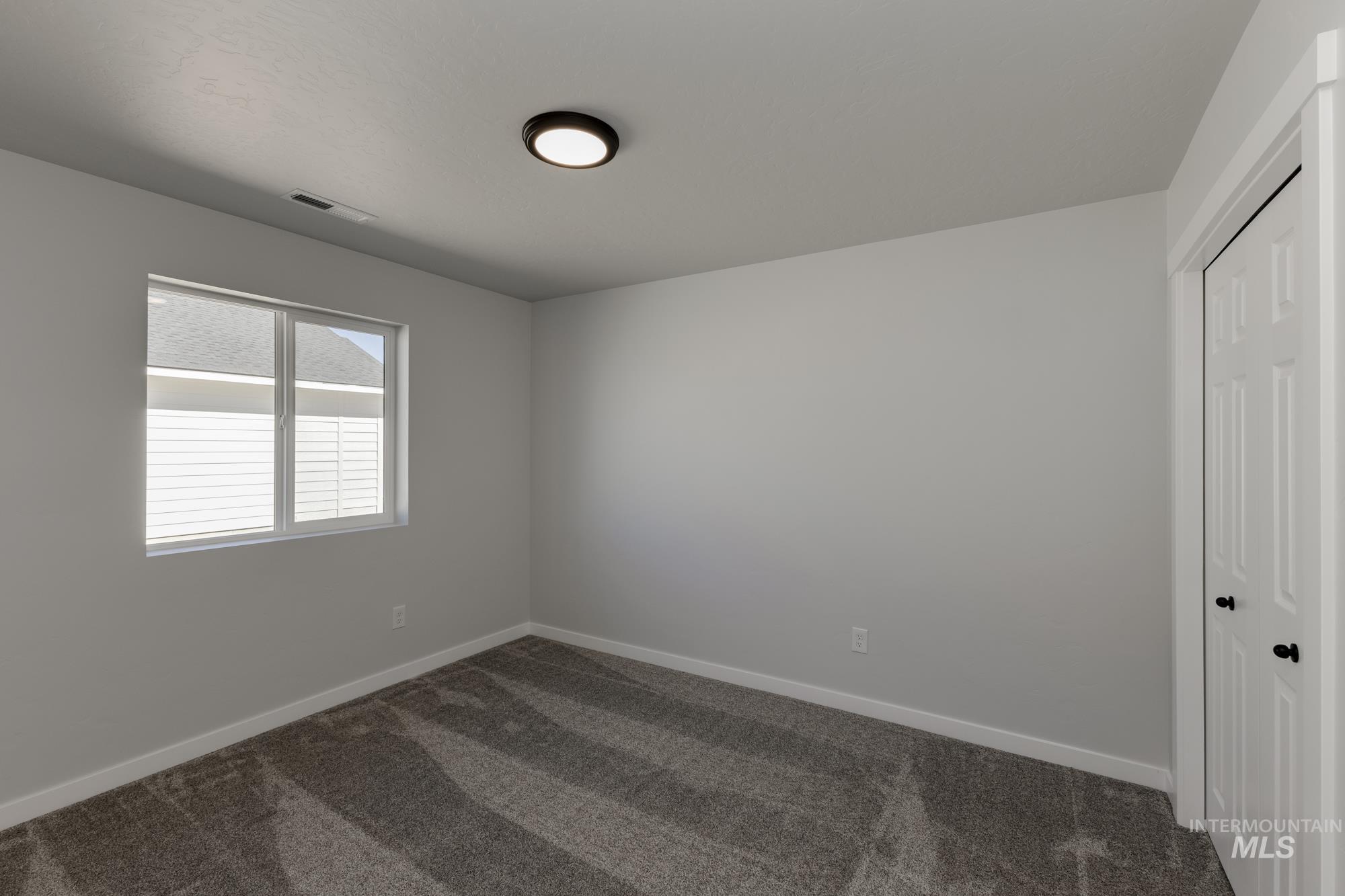 Empty room featuring dark carpet and baseboards