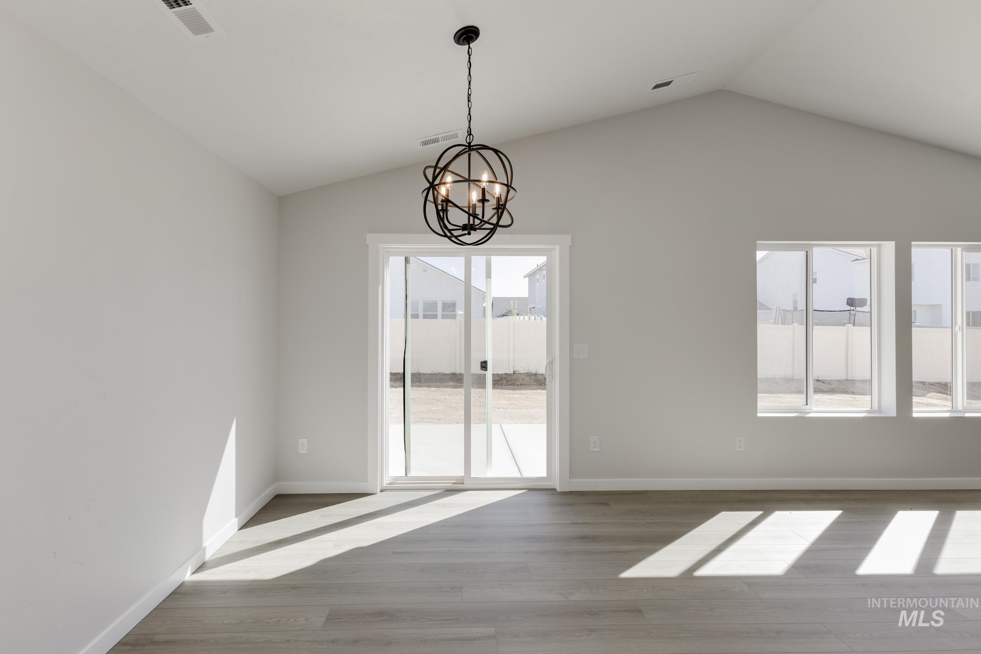 Unfurnished dining area featuring lofted ceiling, light wood finished floors, and a chandelier