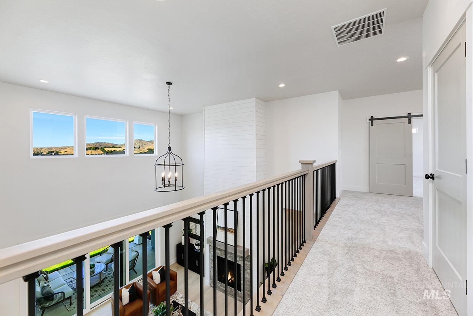 Hall with a barn door, a chandelier, and light colored carpet