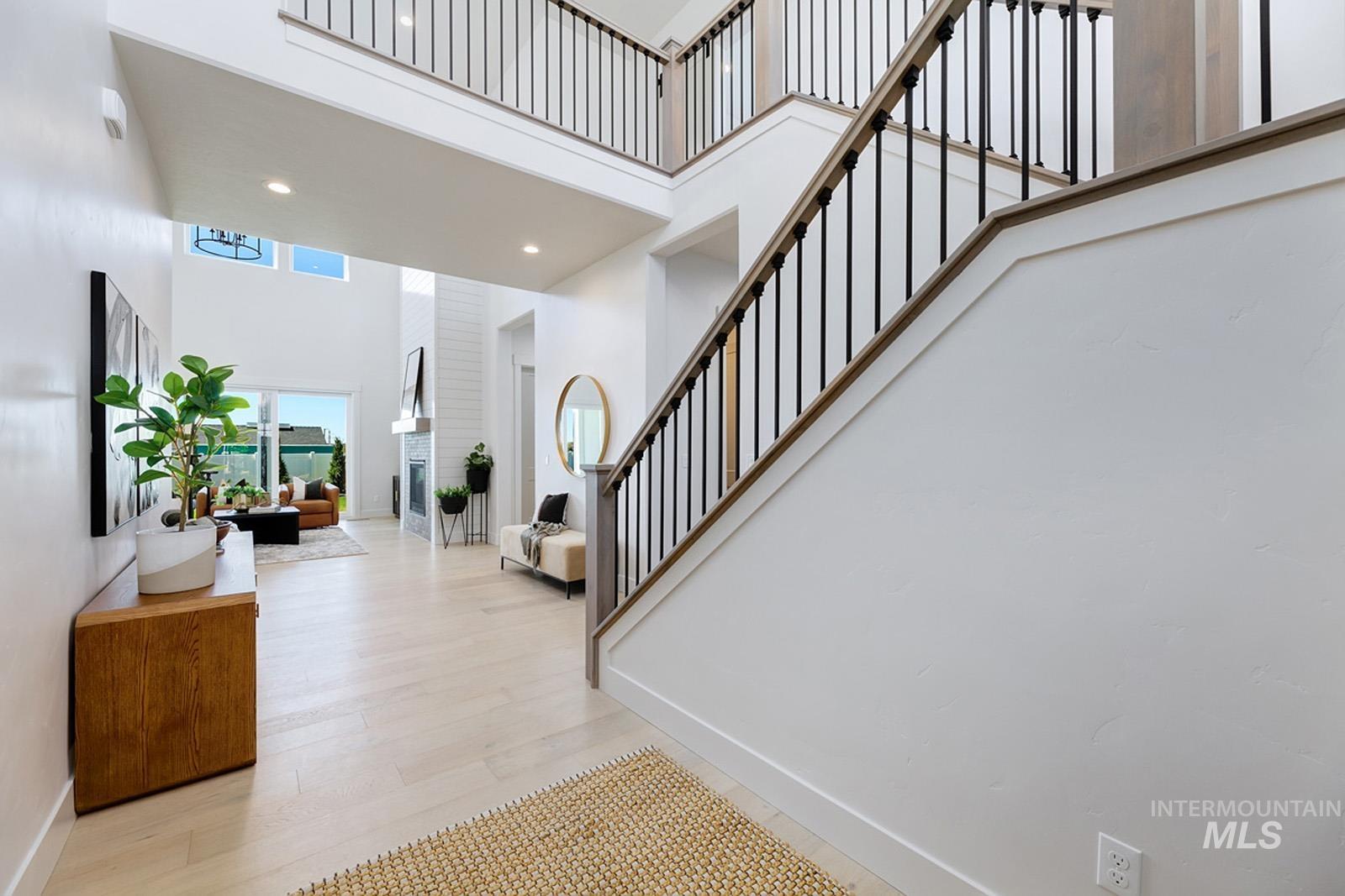 Staircase with a high ceiling, wood finished floors, and recessed lighting