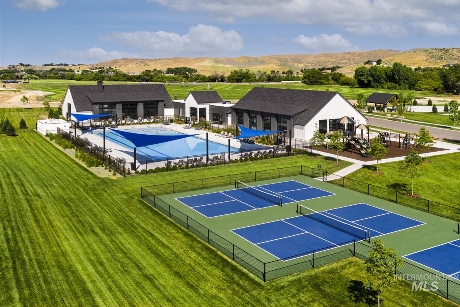 View of tennis court featuring a mountain view, a patio area, and a community pool