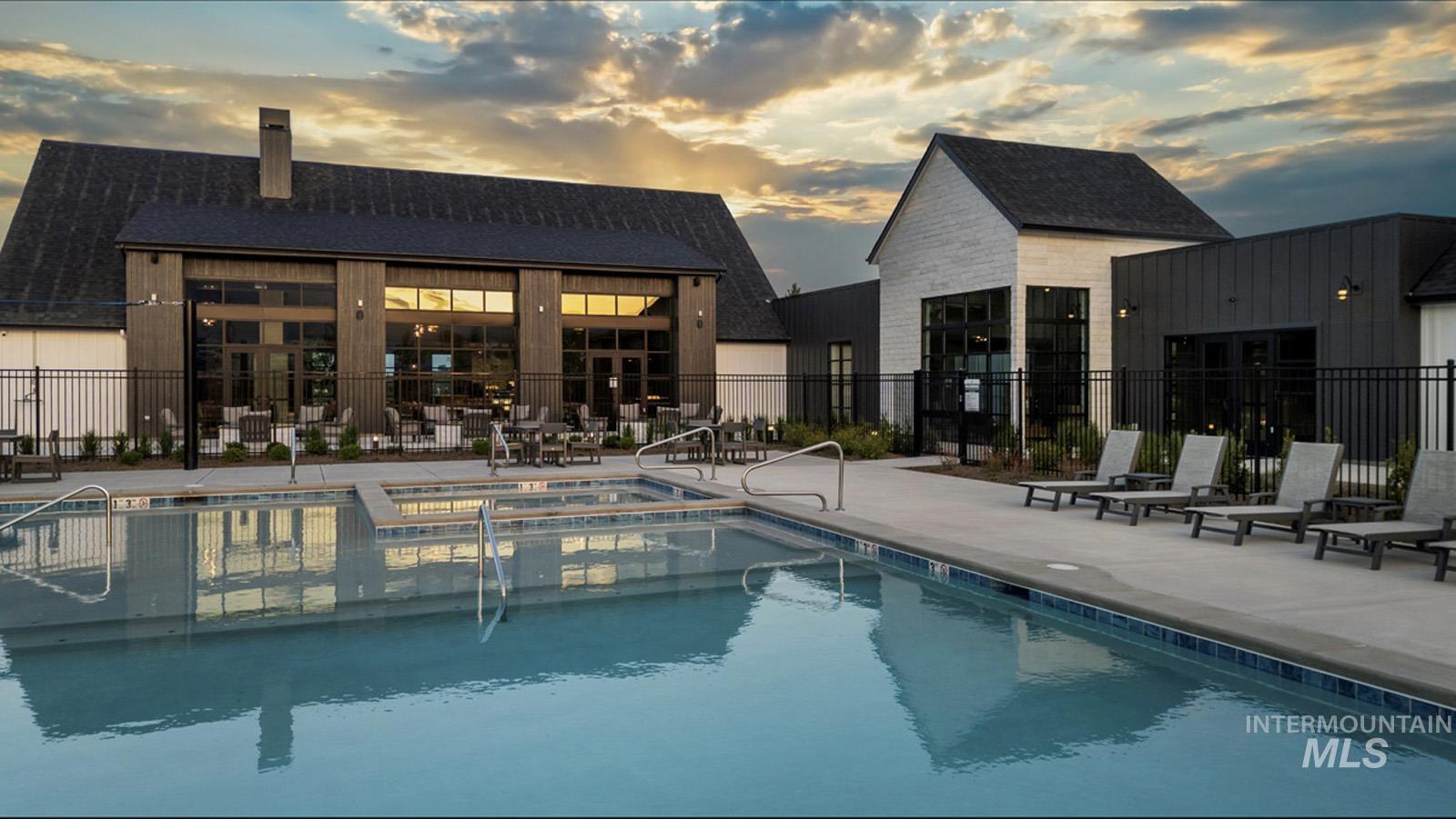 Pool at dusk featuring a patio area and a pool with connected hot tub