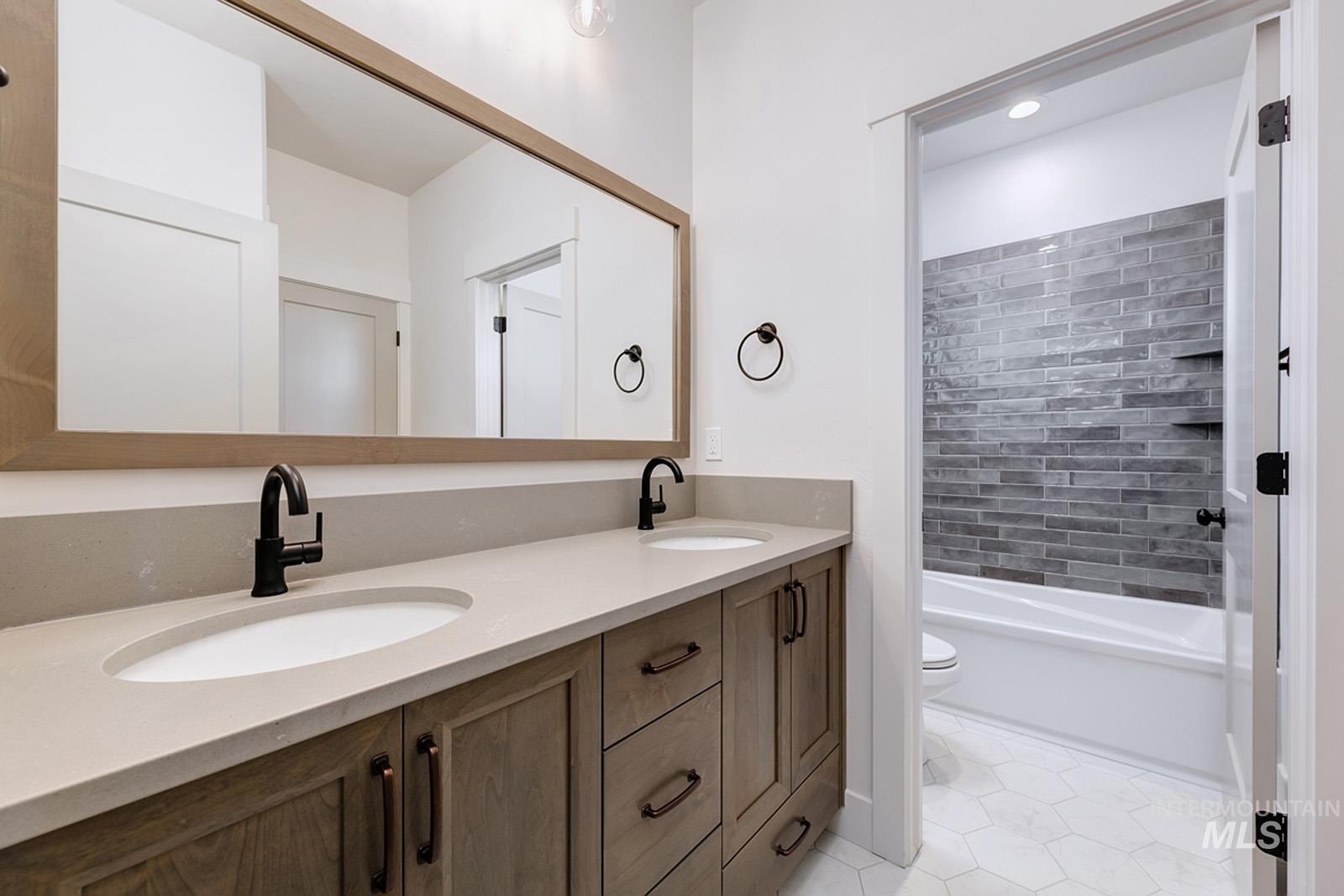 Bathroom with double vanity, light tile patterned flooring, shower / washtub combination, and recessed lighting