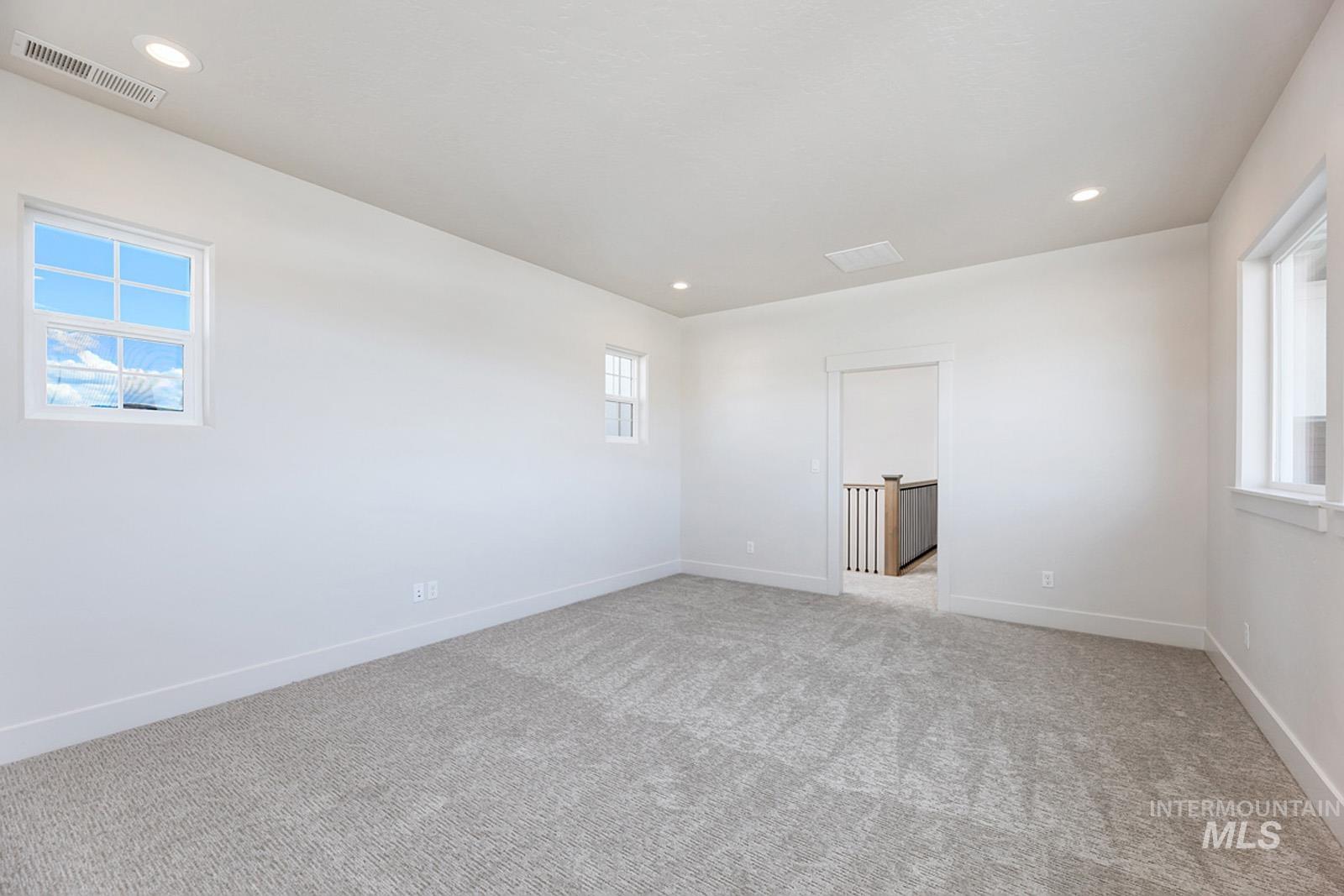 Unfurnished room with healthy amount of natural light, light colored carpet, and recessed lighting