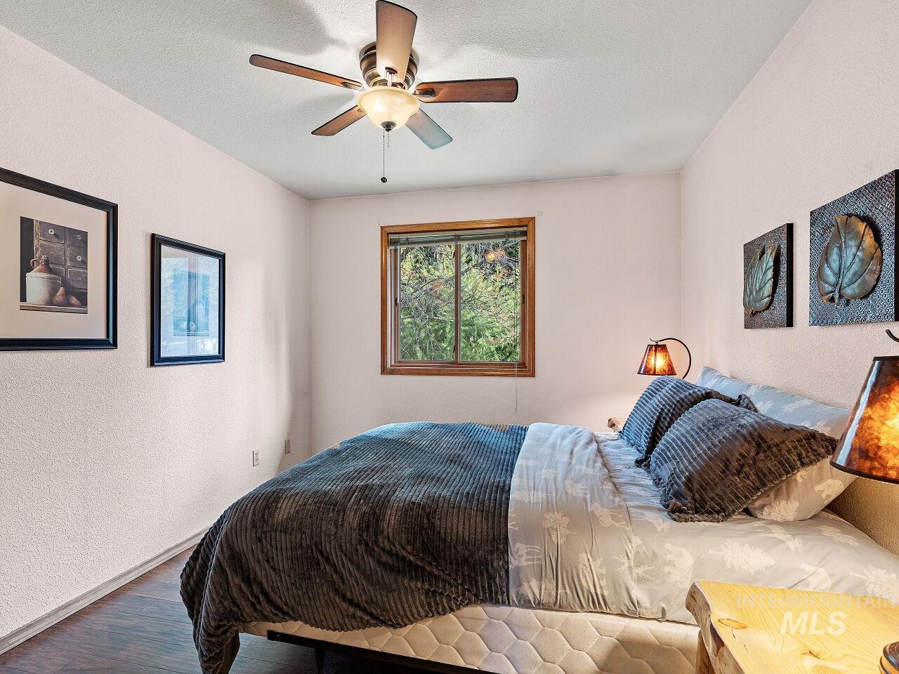 Bedroom with wood finished floors, a textured wall, and ceiling fan