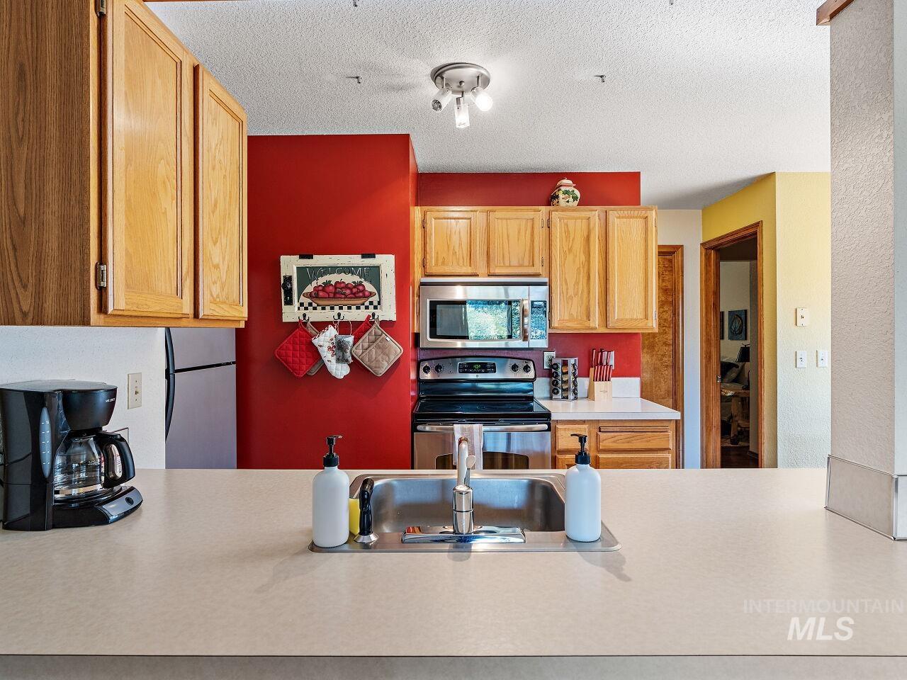Kitchen with appliances with stainless steel finishes, light countertops, and a textured ceiling